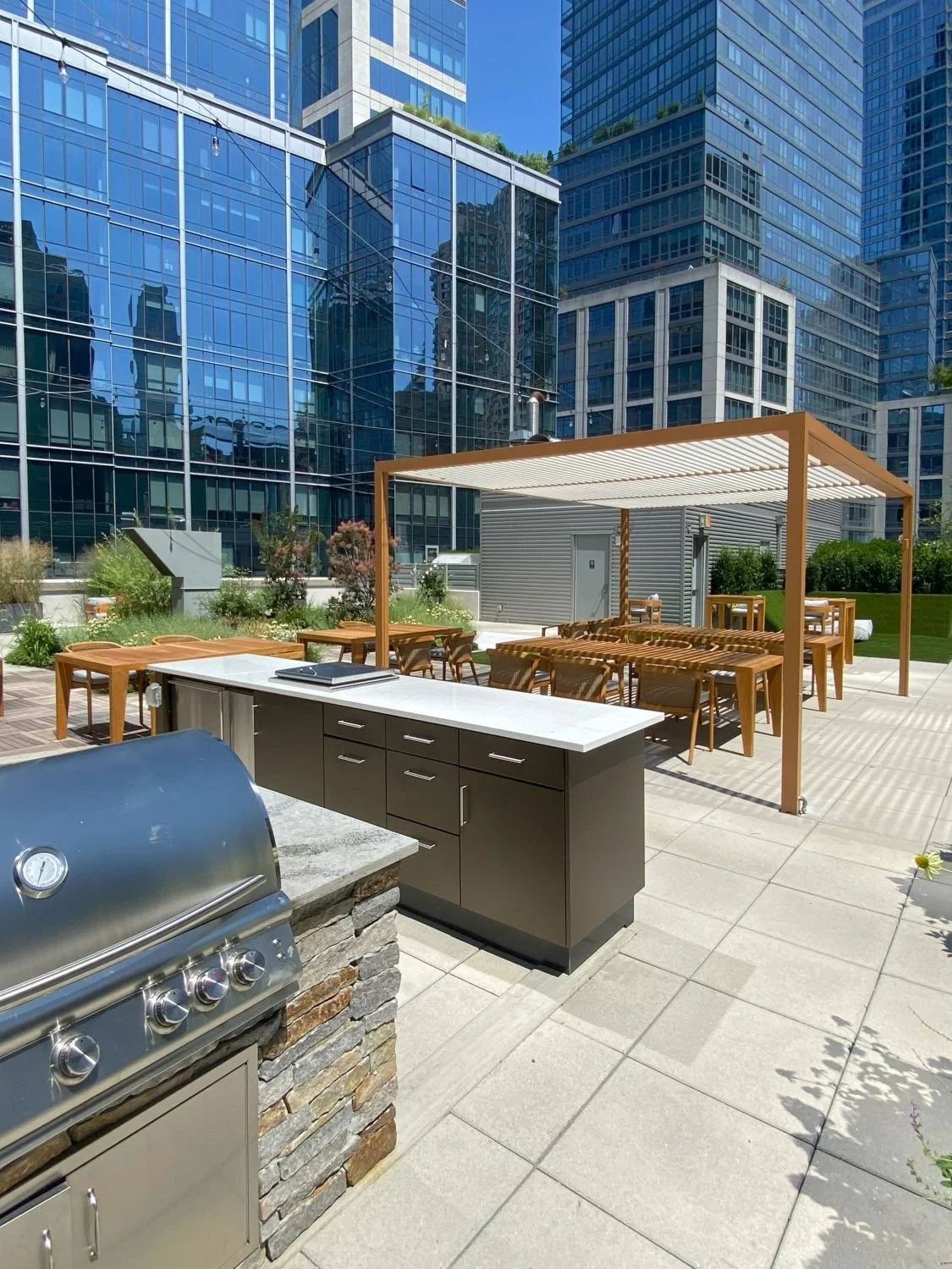 Rooftop outdoor kitchen, grill, bar, and a pergola for dining in NYC