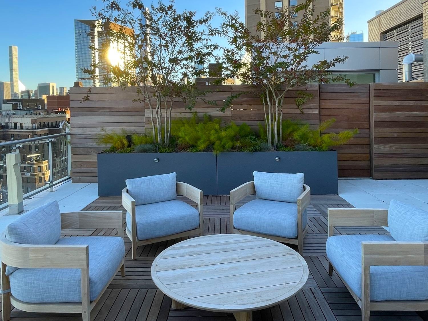 Wood decking and outdoor furniture on a NYC rooftop amenity space. Custom Ipe Fence