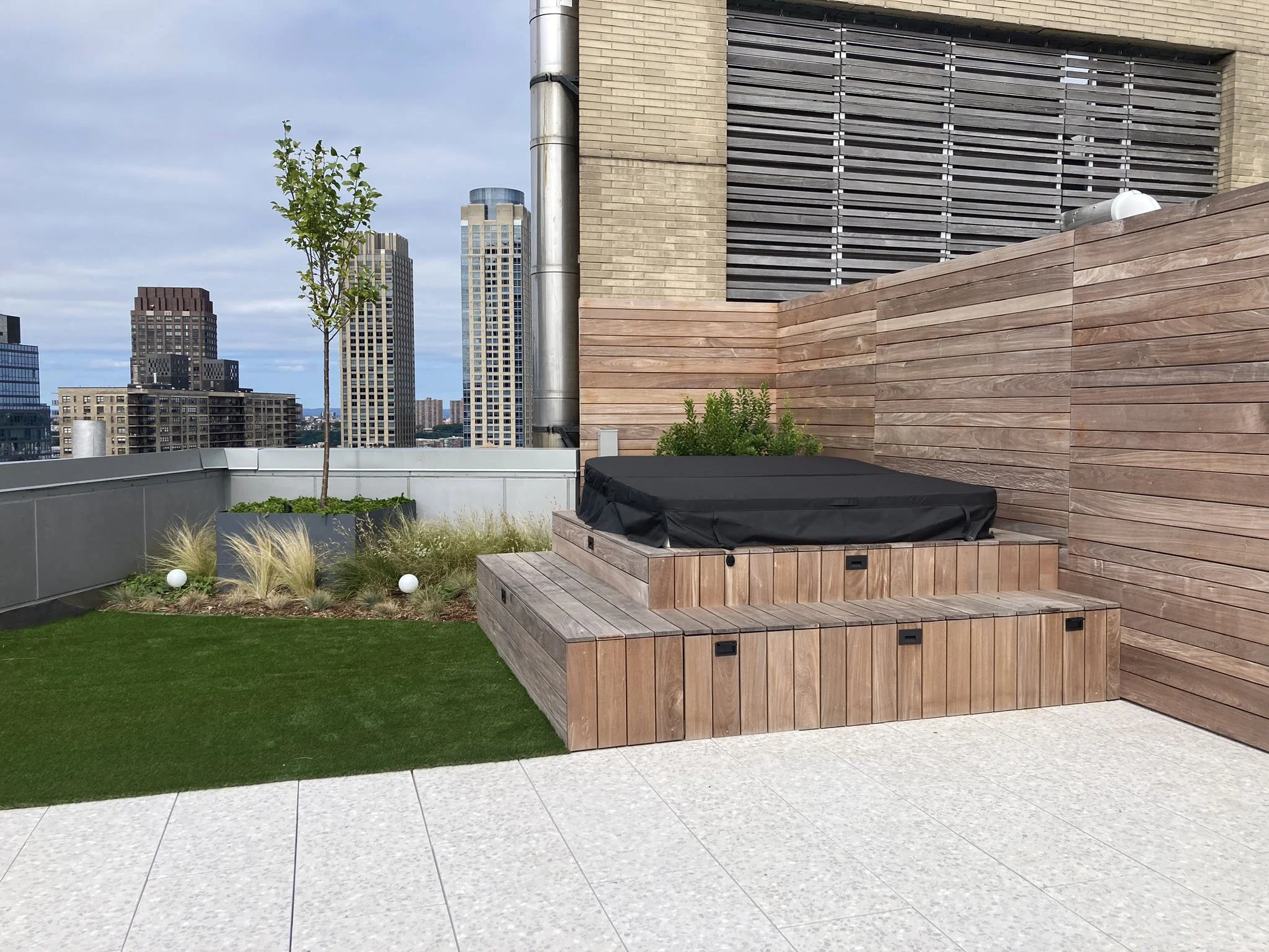 Rooftop amenity space with turf, hot tub, wood deck, and a privacy ipe fence.