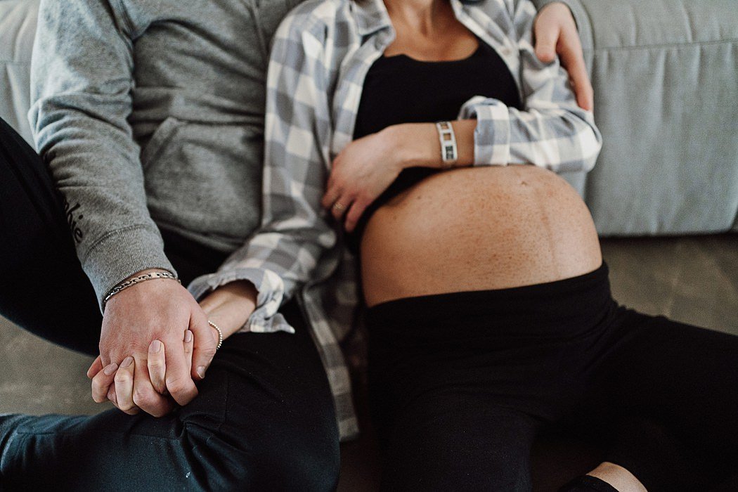 Profilo di donna incinta vicino a una finestra con luce soffusa, in un momento di intimità.