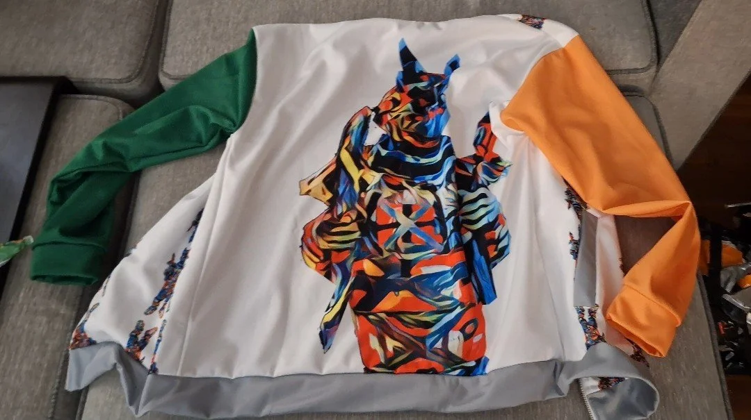 A sports jersey with multicolored abstract design of a horse's head, featuring green, white, orange, and gray sections on khaki-colored furniture.