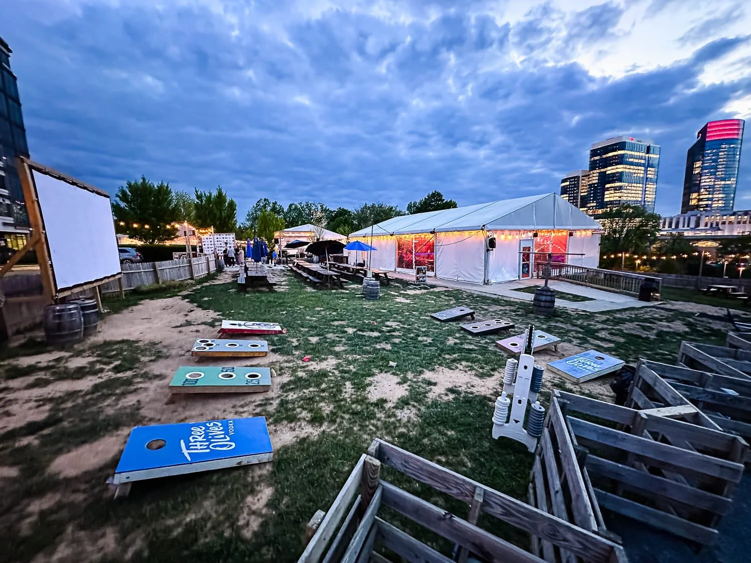 photo of shipgarten, showing the lawn with cornhole, a large screen for projecting on, and picnic tables/beer garden tents in the background