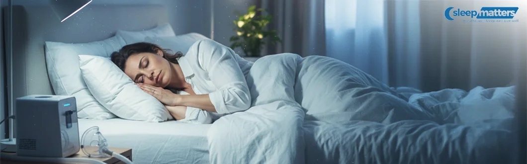 A woman sleeping peacefully in a dimly lit bedroom, with a modern CPAP machine and mask placed on the nightstand next to her bed.