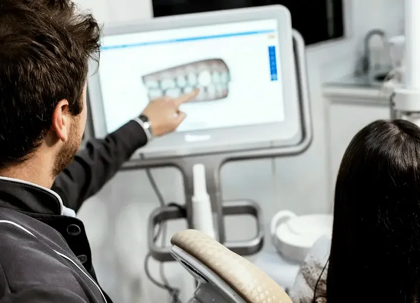 A dentist showing a patient a 3D digital scan of their teeth on a high-tech monitor, used to design a custom oral appliance for sleep apnoea therapy.