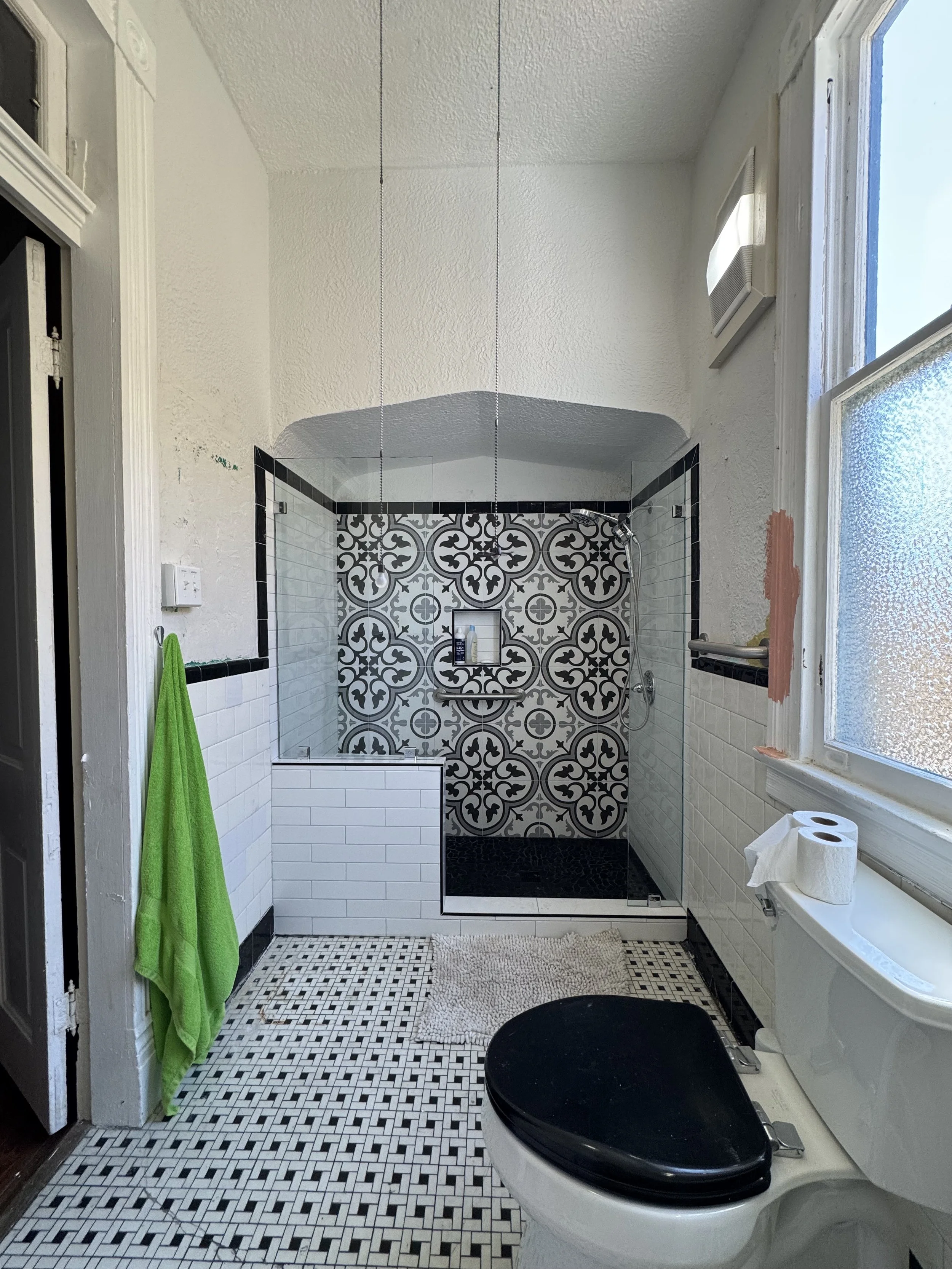 Modern tiled shower remodel with glass enclosure and patterned tile feature wall in New Orleans bathroom renovation