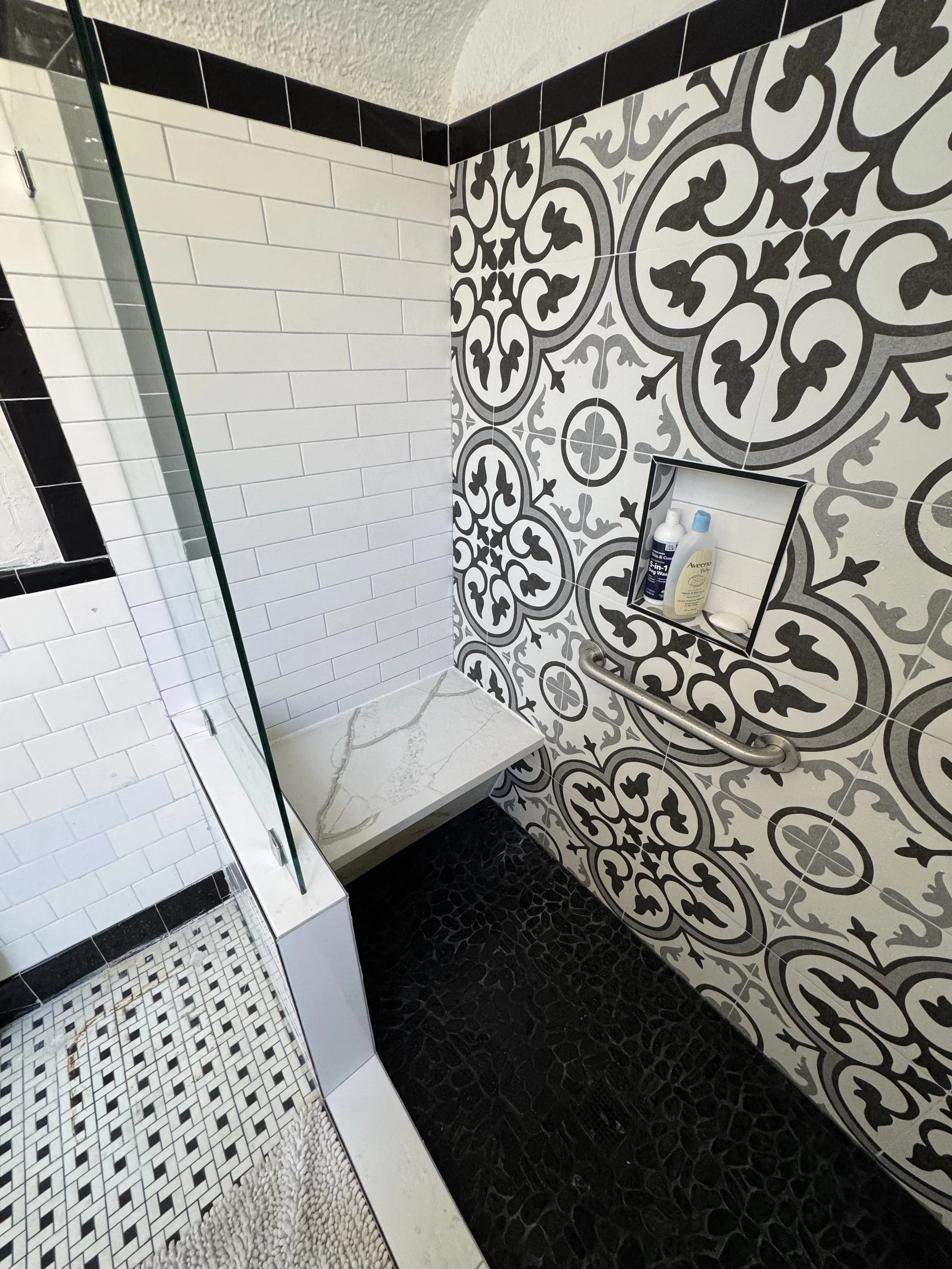 Modern tiled shower remodel with glass enclosure and patterned tile feature wall in New Orleans bathroom renovation