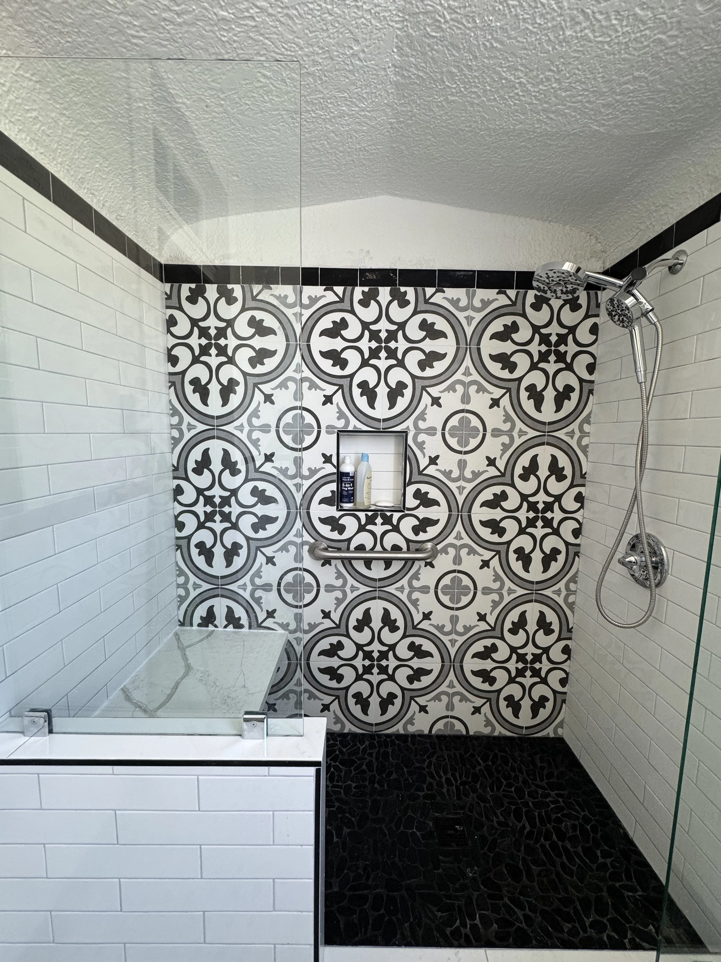 Modern tiled shower remodel with glass enclosure and patterned tile feature wall in New Orleans bathroom renovation