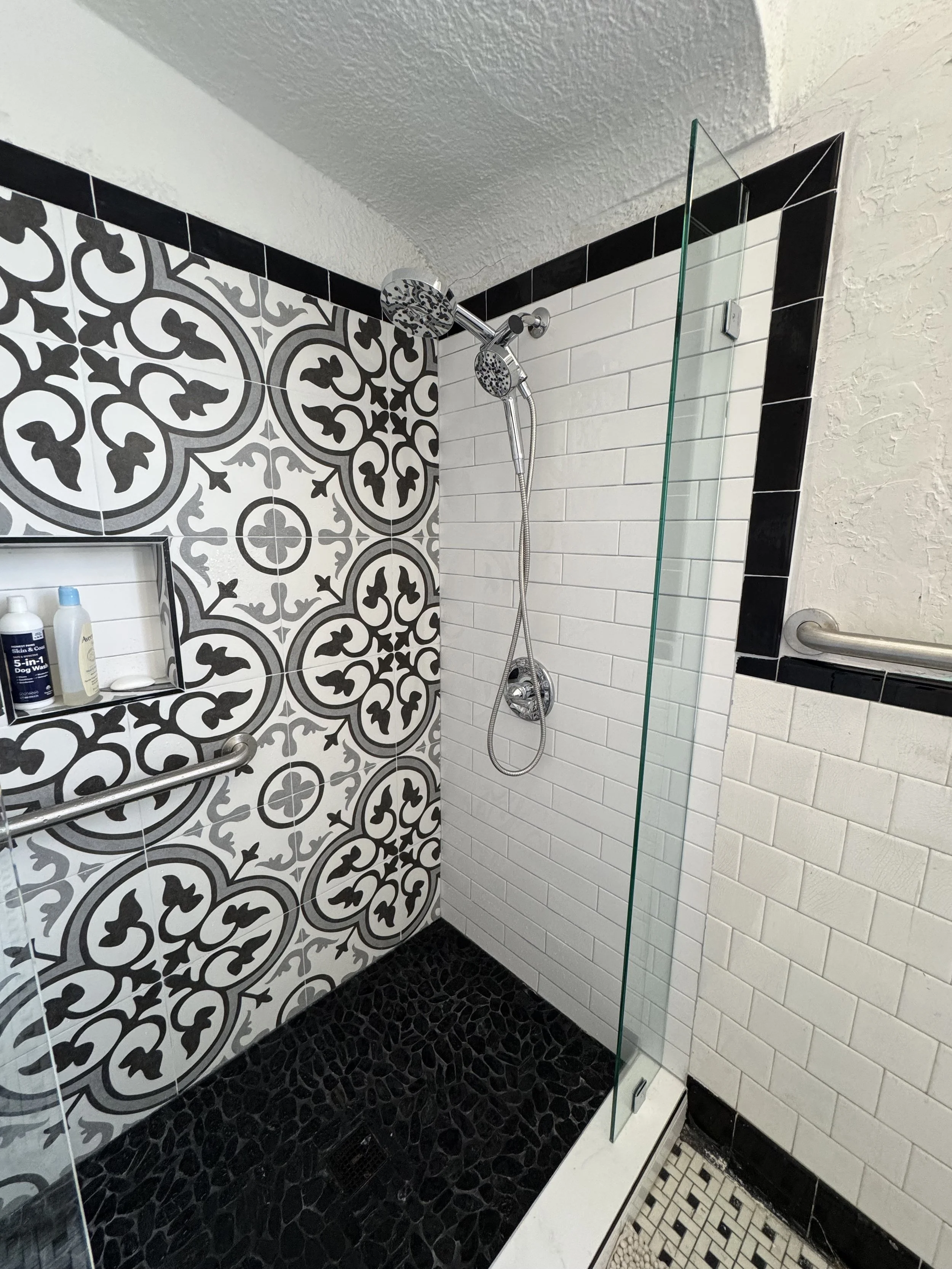 Modern tiled shower remodel with glass enclosure and patterned tile feature wall in New Orleans bathroom renovation