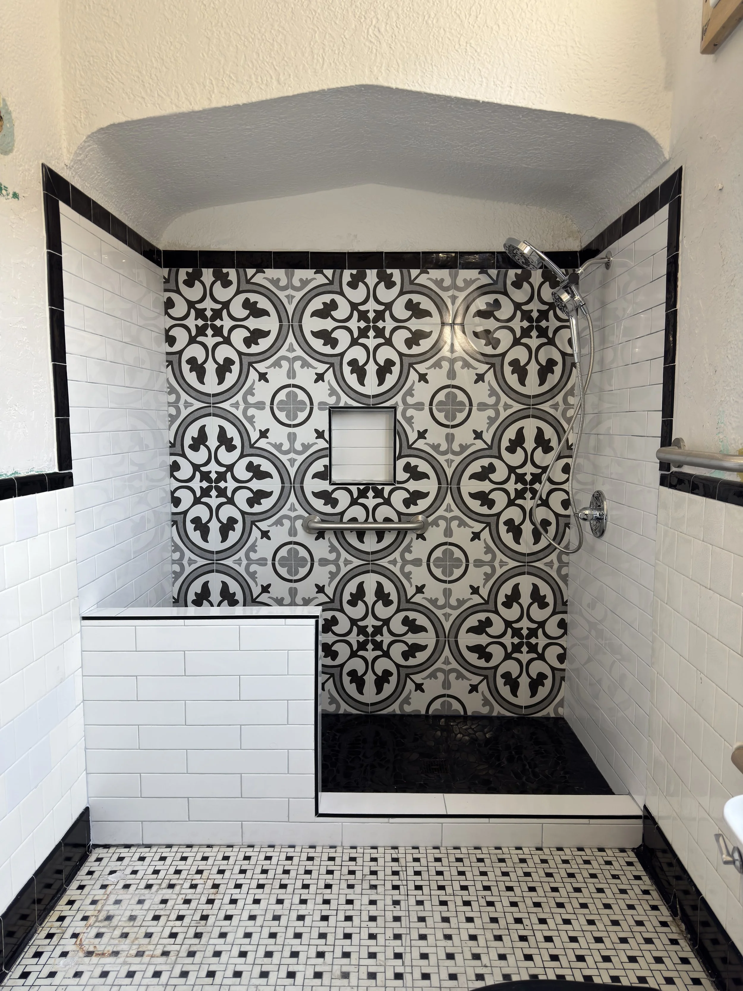 Modern tiled shower remodel with glass enclosure and patterned tile feature wall in New Orleans bathroom renovation