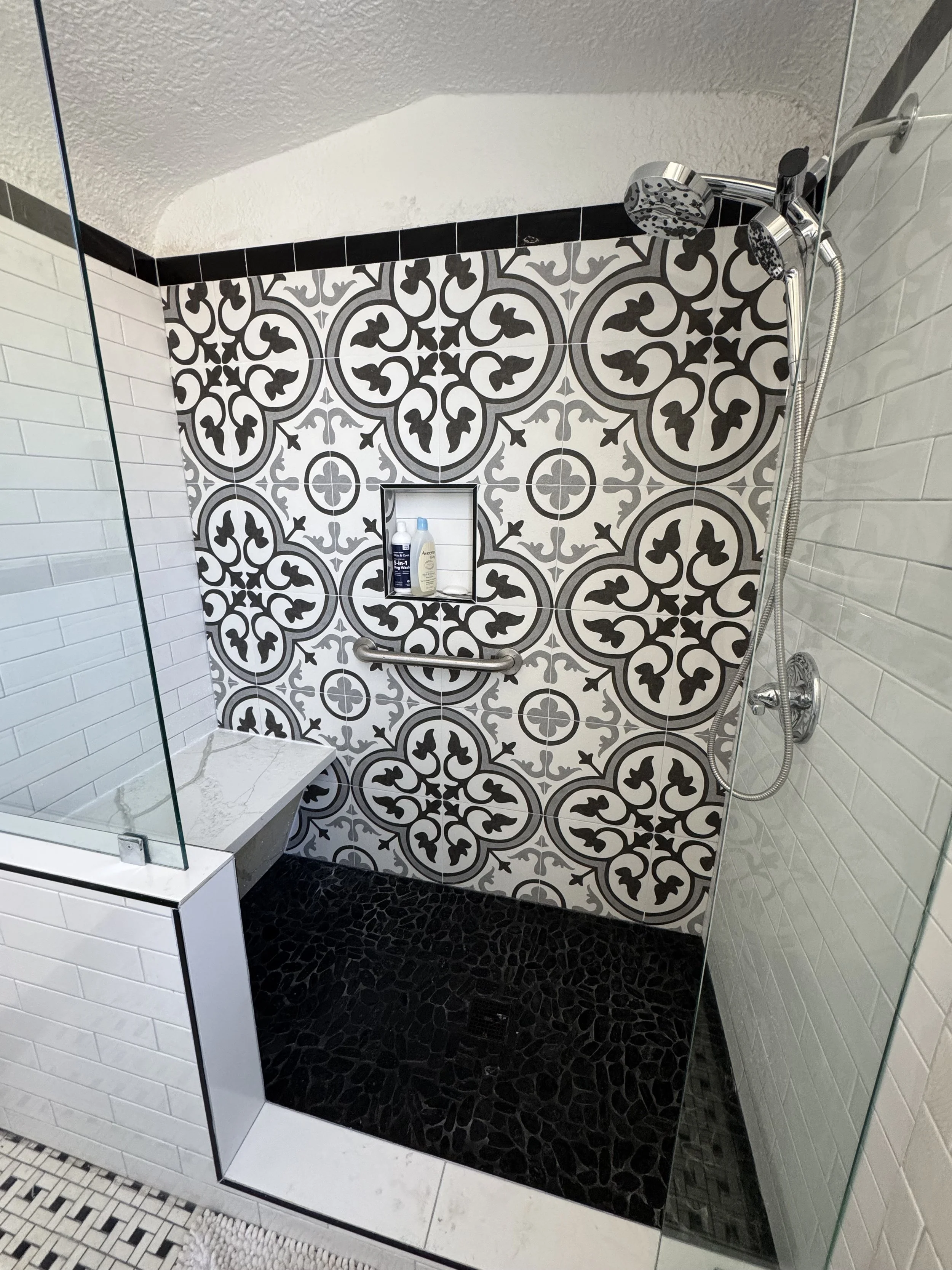 Modern tiled shower remodel with glass enclosure and patterned tile feature wall in New Orleans bathroom renovation