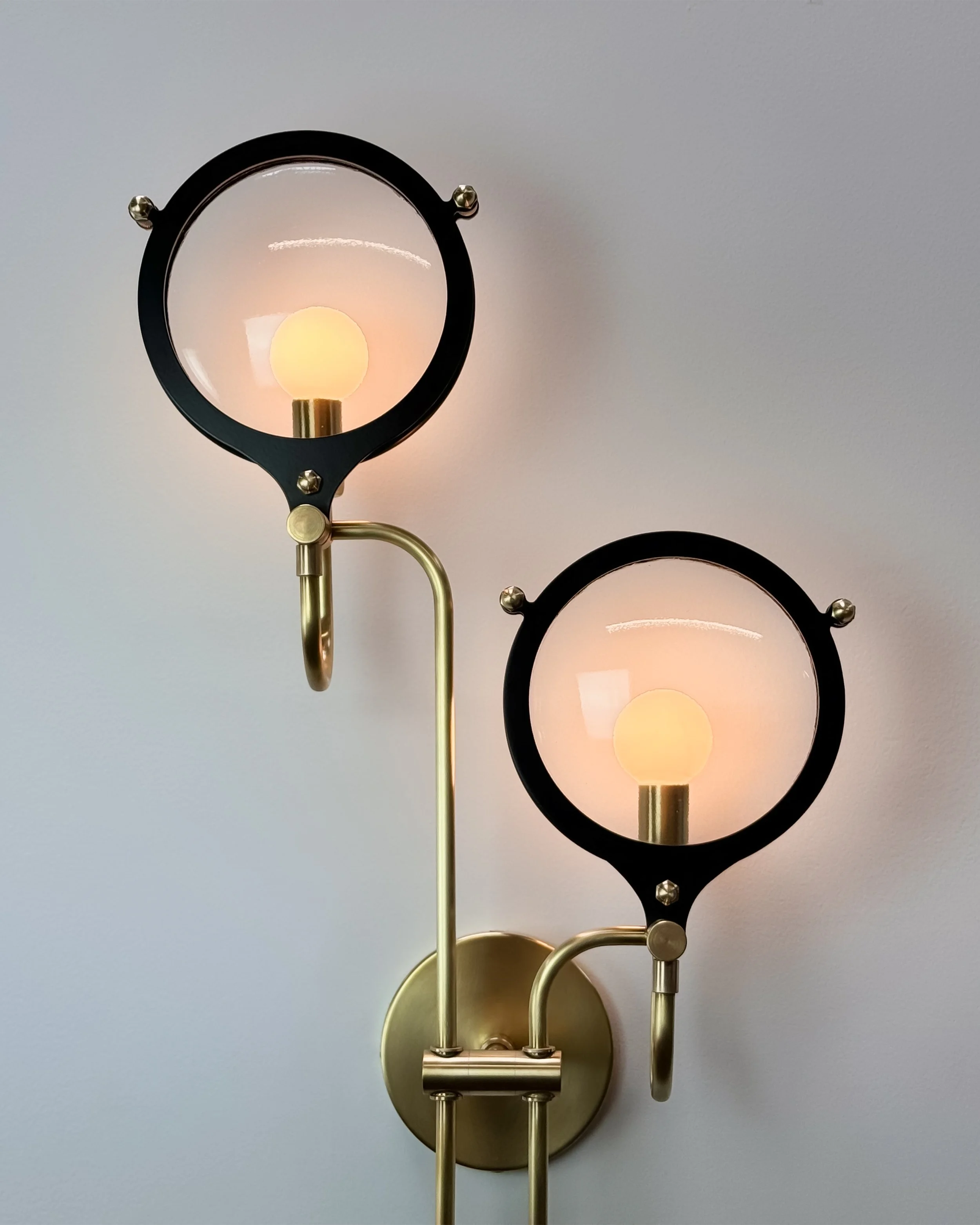 Double Lens Sconce by Neptune Glassworks—wall-mounted fixture with staggered glass discs framed in brass and steel, inspired by optical instruments. Handcrafted in Los Angeles.