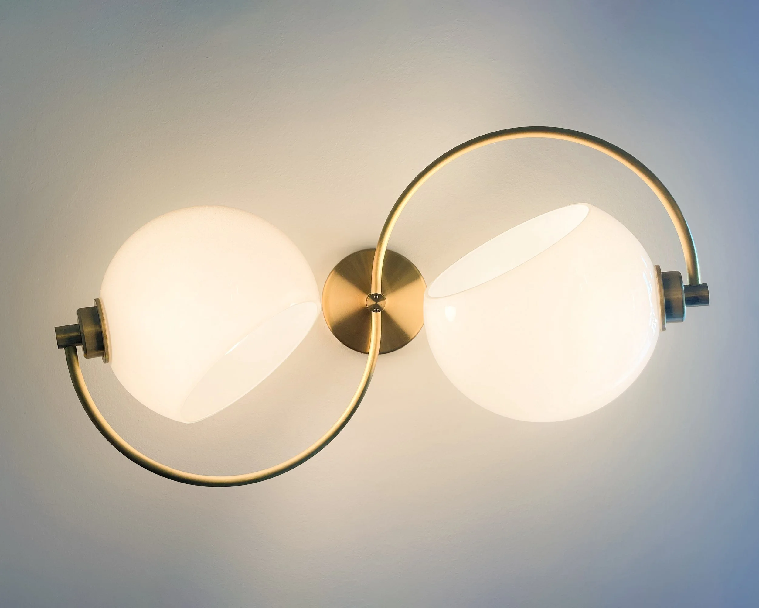 Phase Sconce by Neptune Glassworks—wall-mounted fixture with curved brass arm and glass hemisphere inspired by lunar phases. Handcrafted in Los Angeles.