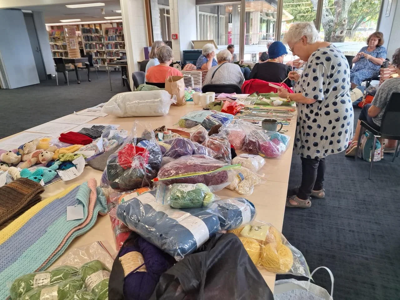 A table full of crafting materials, being looked over by women at a meet up