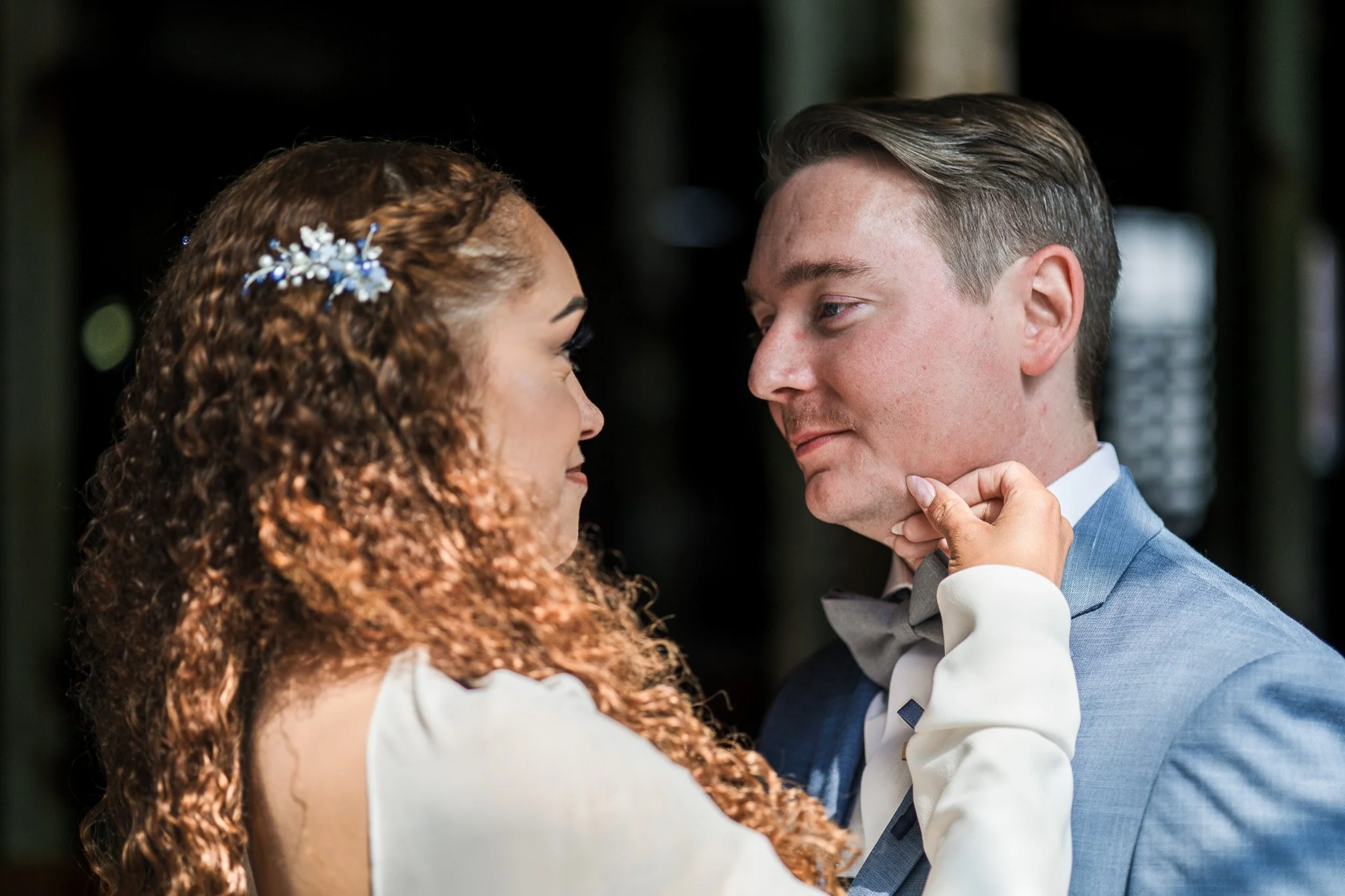 A bride and groom share a close moment during their wedding, gazing into each other's eyes with a gentle touch.