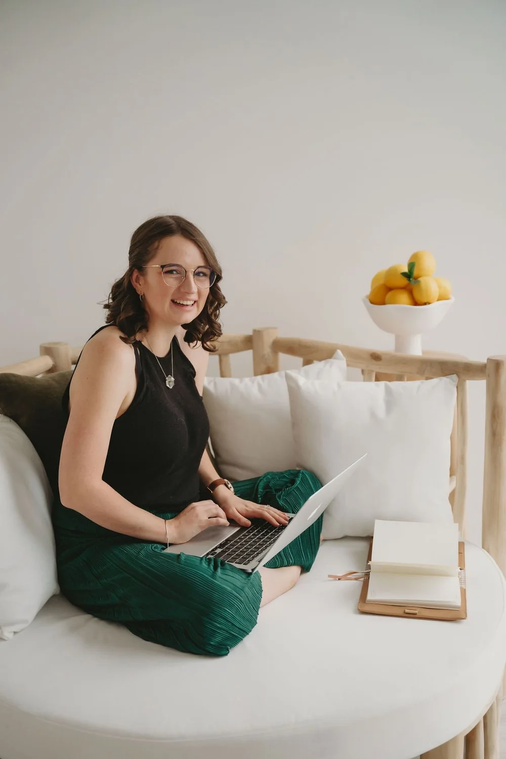 Jade smiling on a white sofa with her laptop