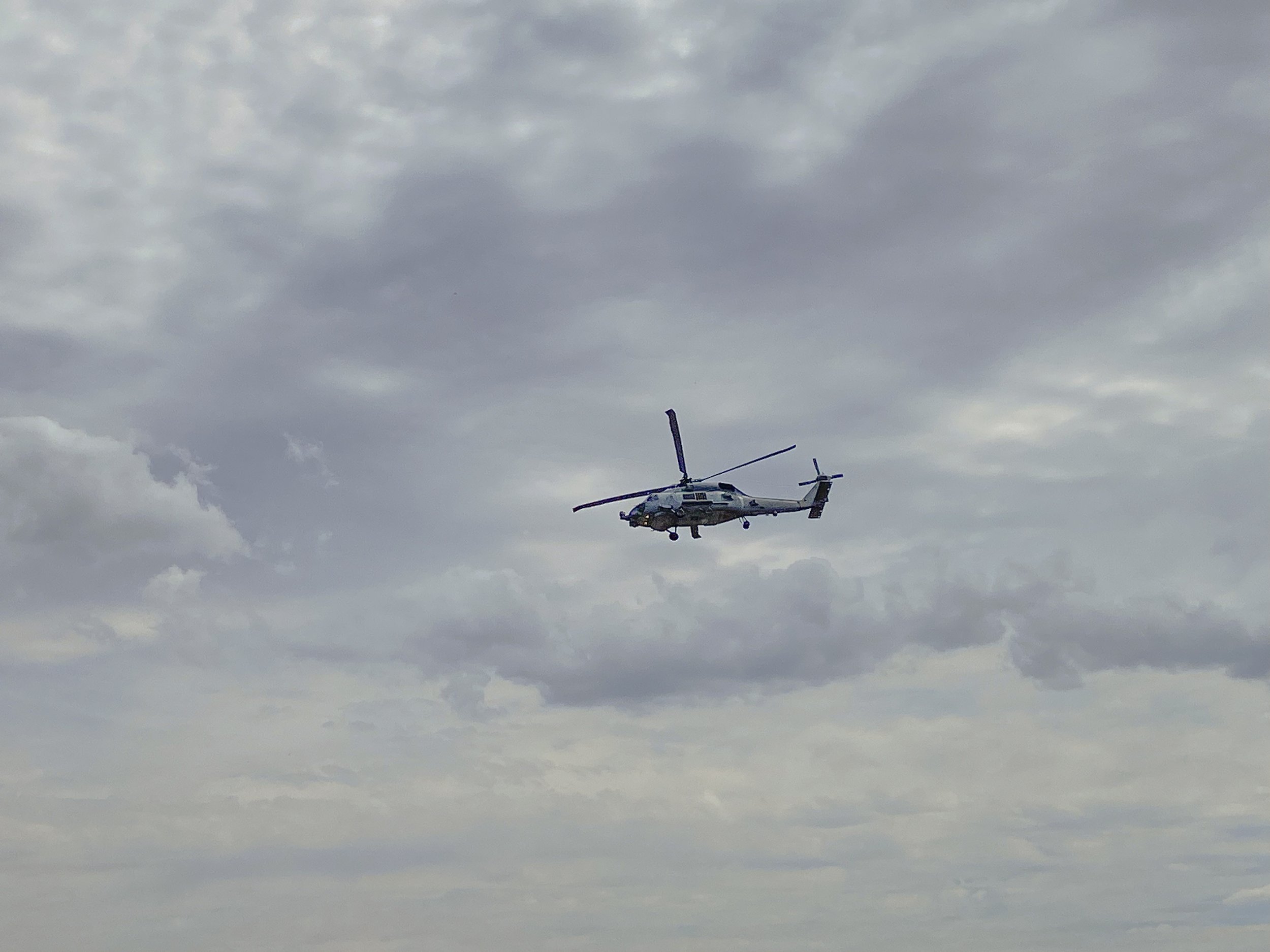 A helicopter flying in a cloudy sky.