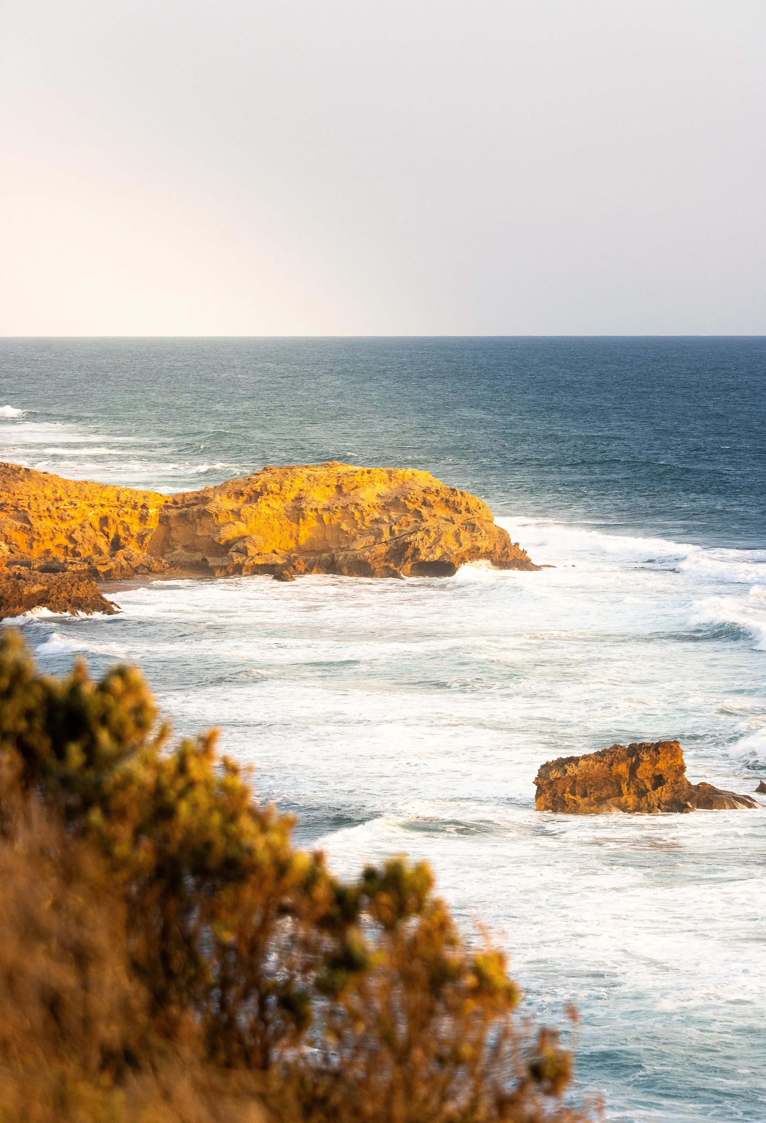 Beach with rocky cliffs and ocean waves during sunset.