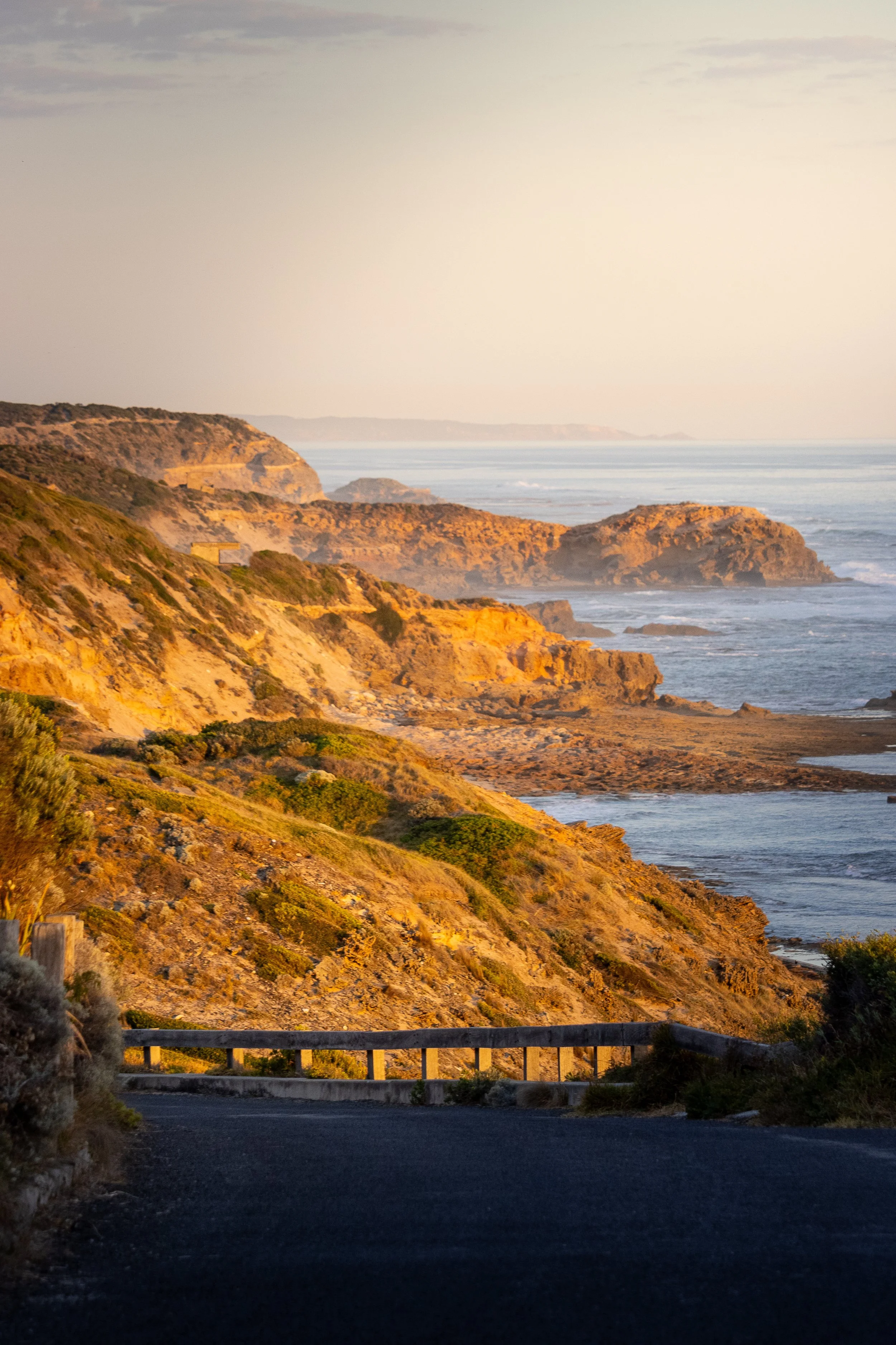 Sunset over a rugged coastal landscape with cliffs and ocean in the background.