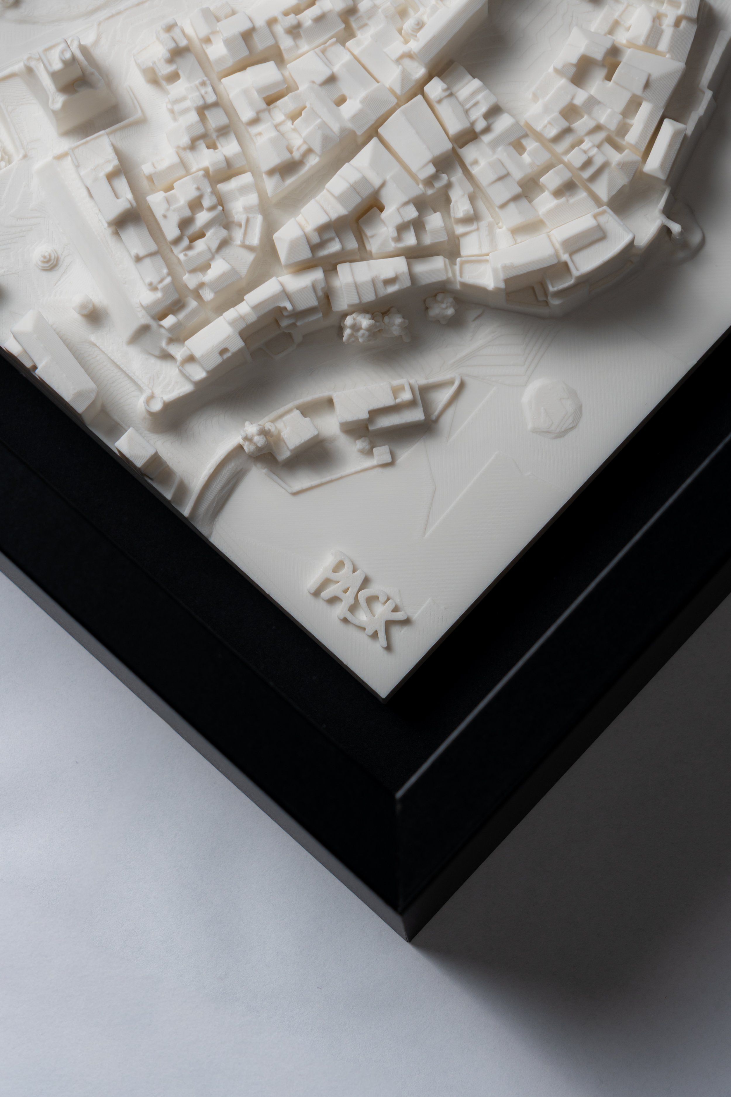 Modello architettonico in miniatura di un'area urbana con edifici e strade, con la scritta 'PASS' sul lato.