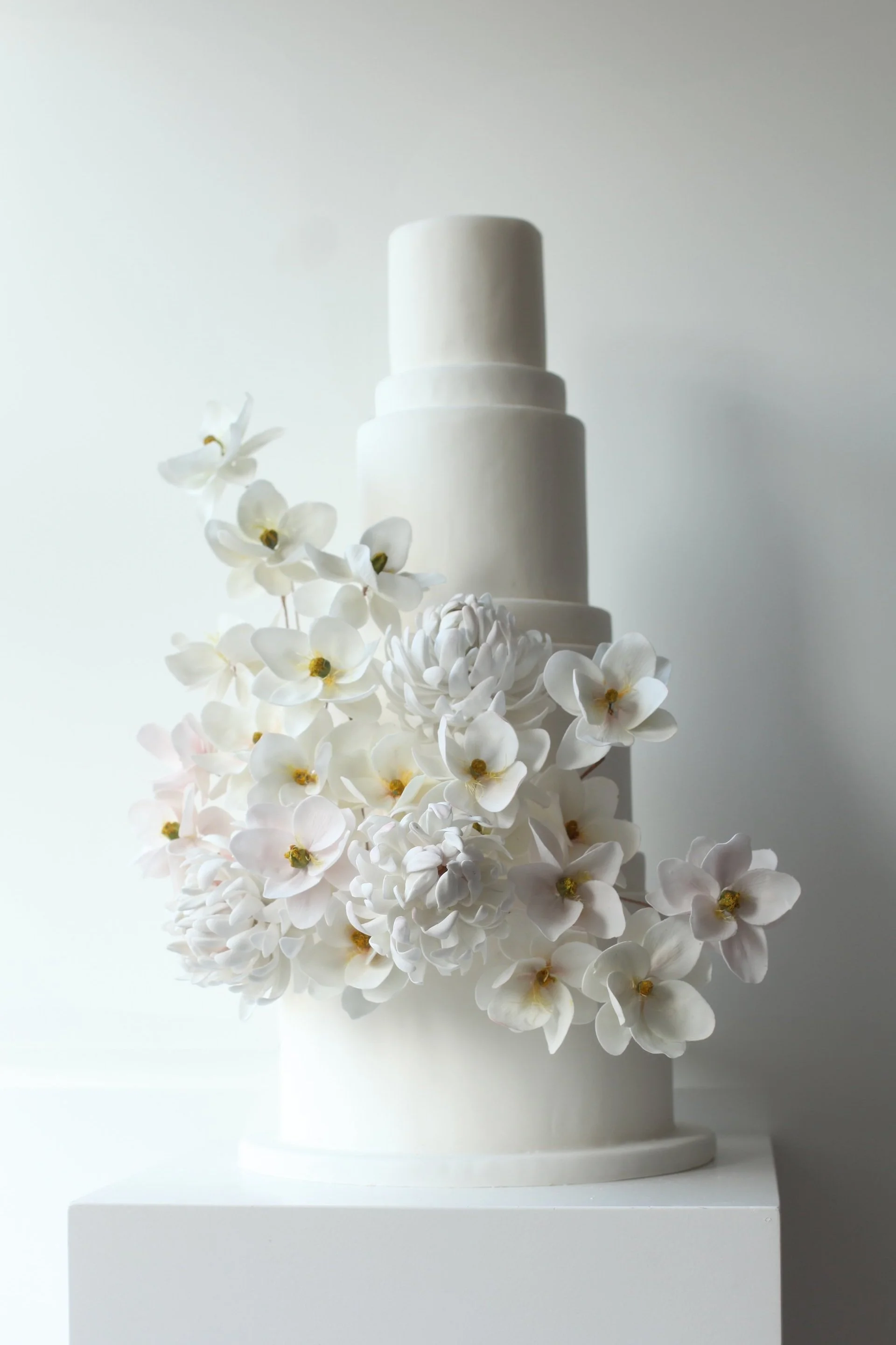 6 tier contemporary white wedding cake with large bouquet of sugar flowers
