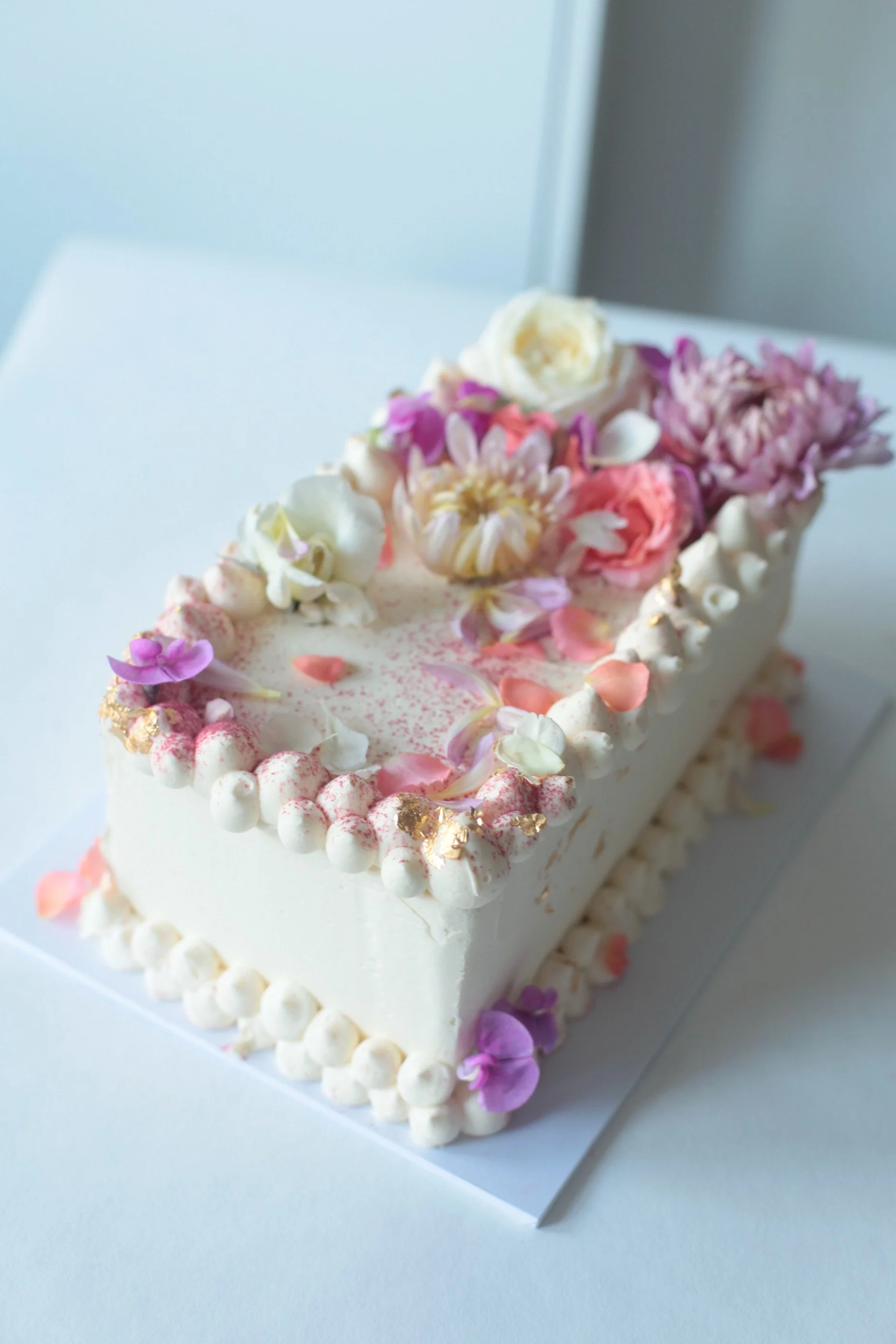 Oblong cake in the style of Violet Cakes, with buttercream and fresh flowers