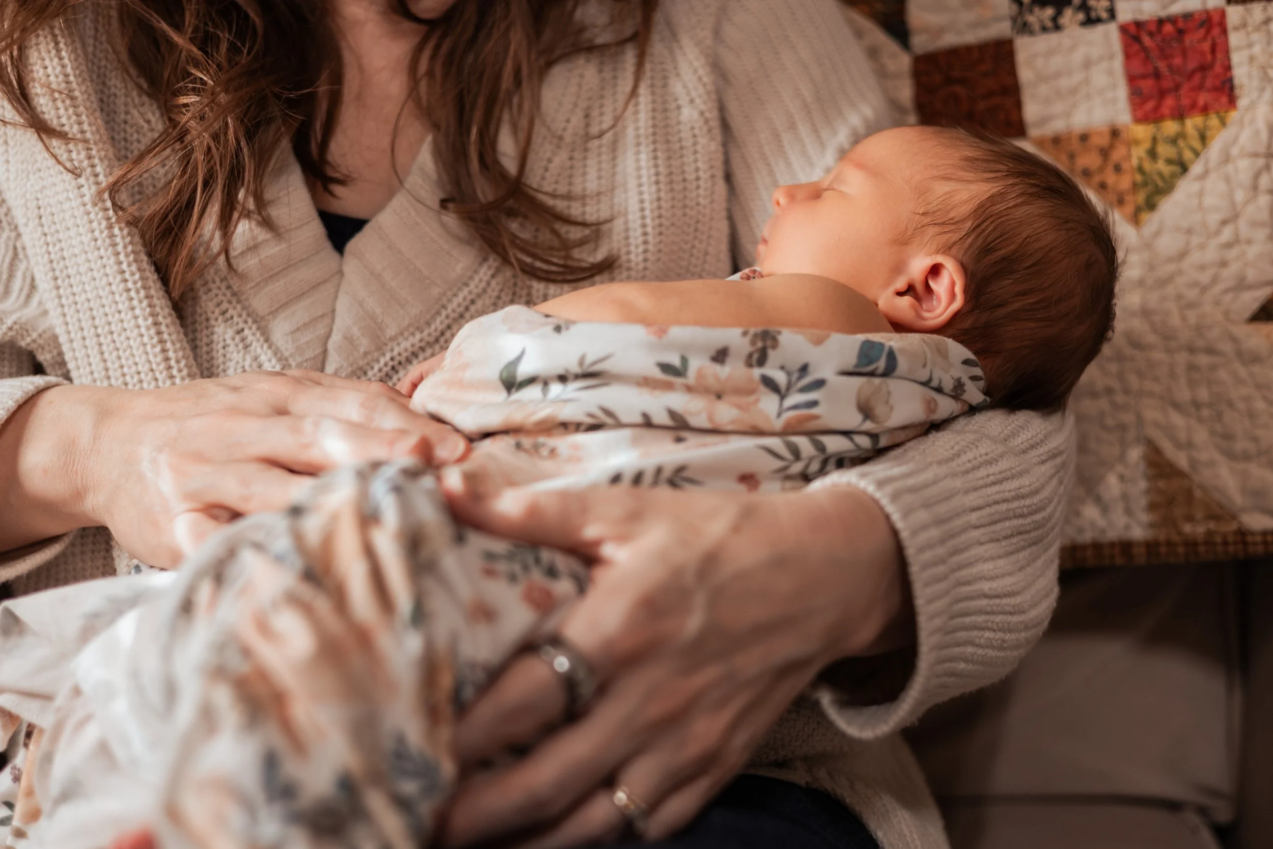 Woman holding a sleeping baby wrapped in a floral blanket during wichita, ks lifestyle newborn session