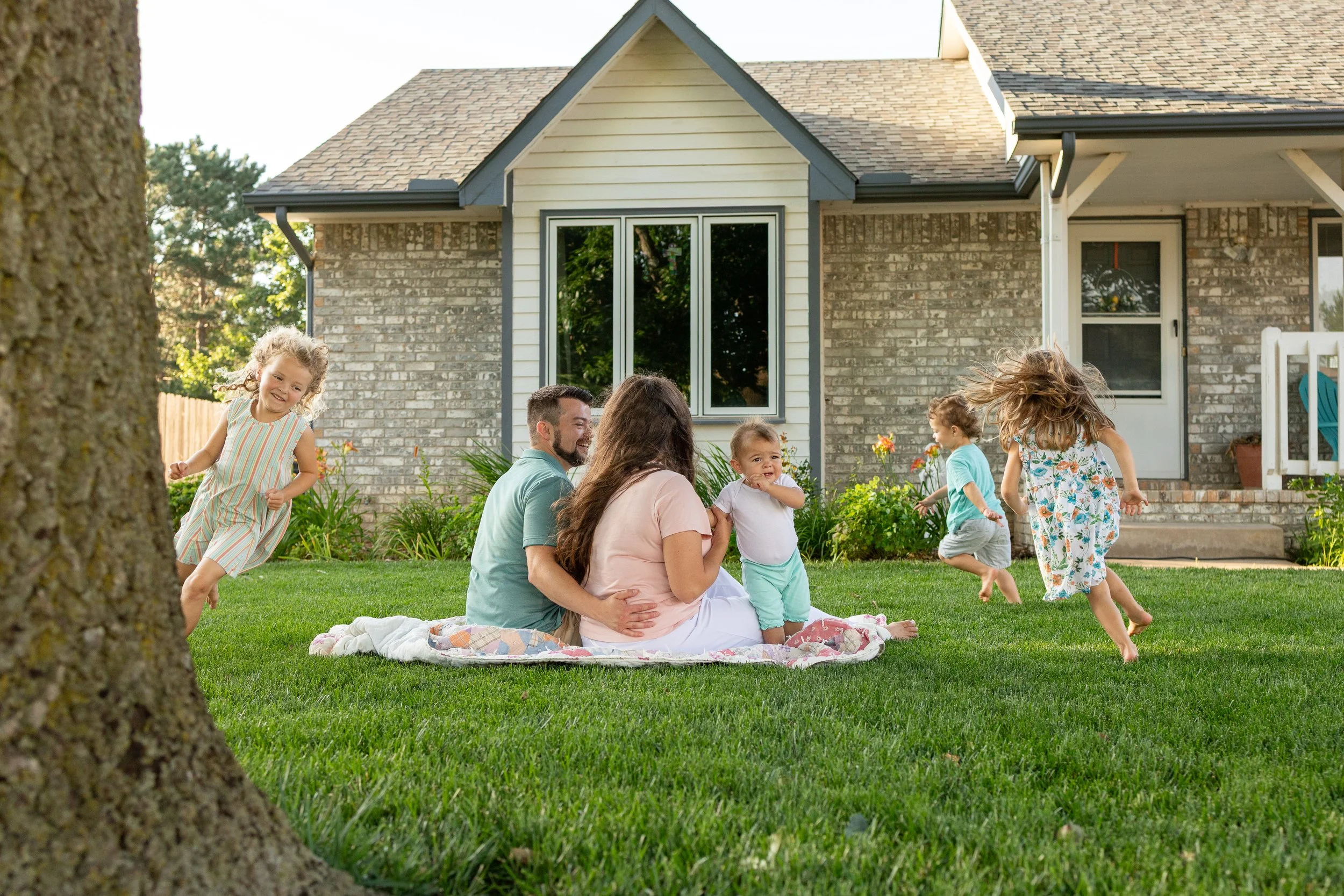 Family in grass with kids running around playing for summer photo sessions at home wichita ks