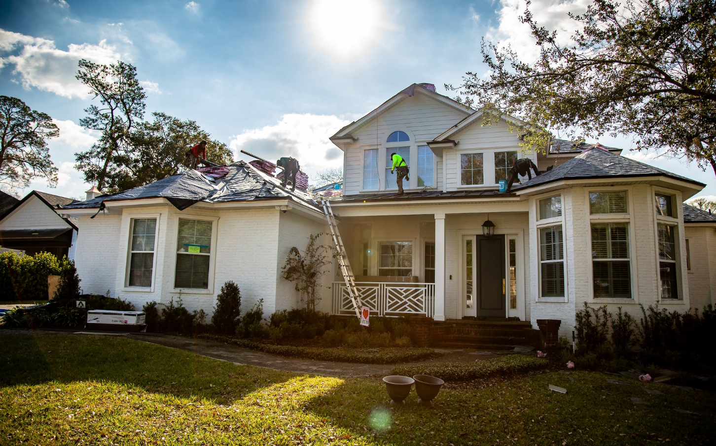 Workers on a roof in St. Augustine replacing the shingles and installing underlayment.