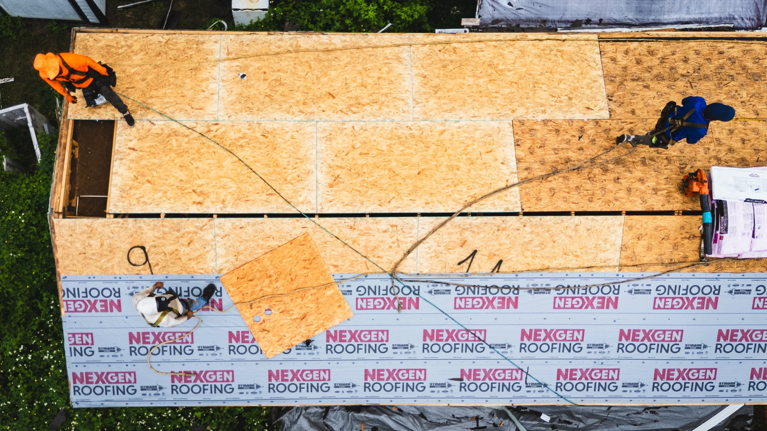 Aerial view of NexGen Roofing crew installing plywood roof decking and underlayment on residential roof replacement project.