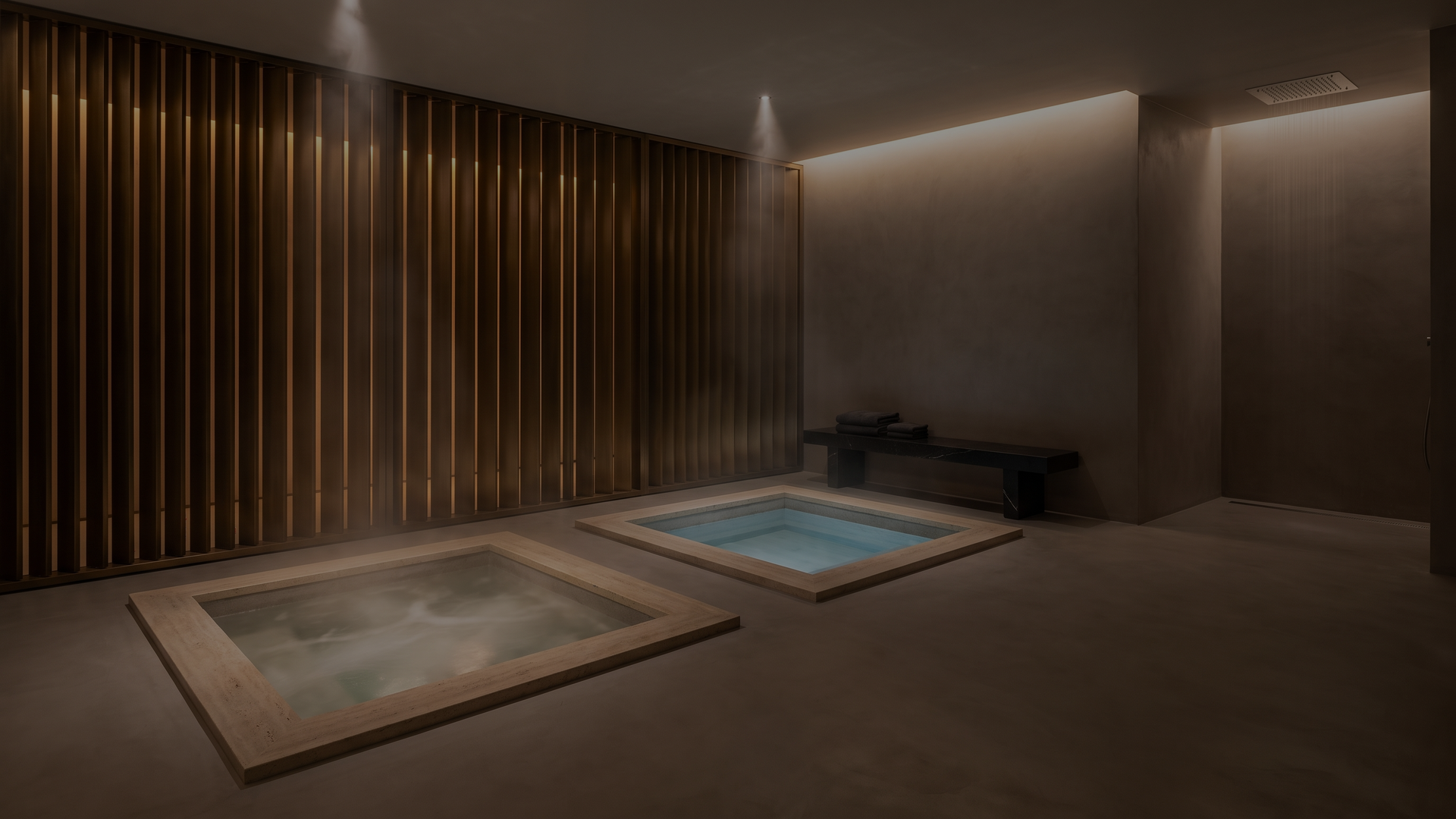 Indoor spa room with two square hot tubs, wooden slat wall, dim lighting, and a bench with towels.