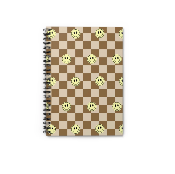 Spiral notebook with a chessboard pattern background and smiley face stickers on each square.