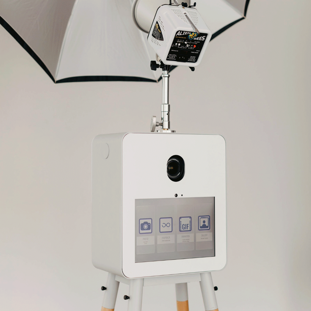 photo booth attendant capturing photos for guests as they pose in front of printer booth and receive their high quality prints and digital sms