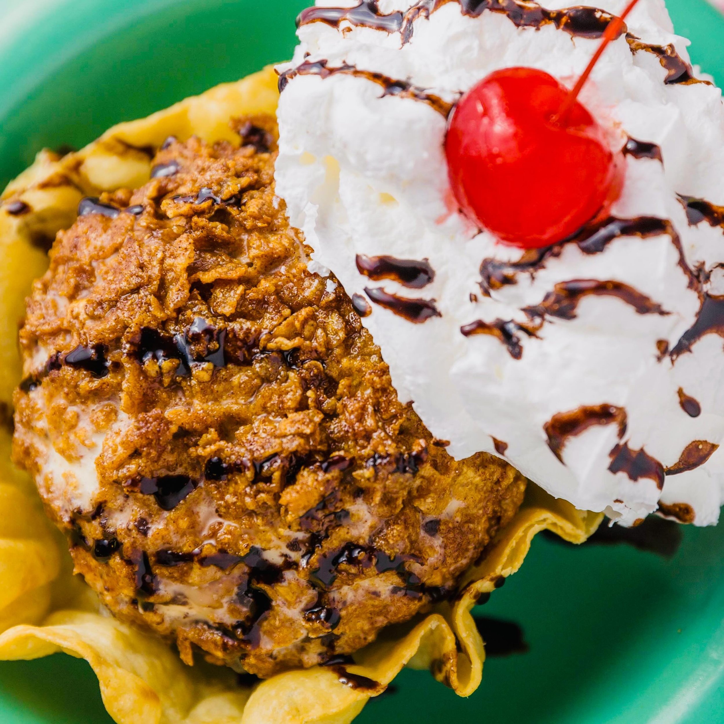 Alrighty, folks! Get ready for a sweet sensation like no other! Satisfy those munchies with our Fried Ice Cream extravaganza! Lord have mercy! Picture this: chocolate chip ice cream, rolled up in a crunchy coating, and then topped with decadent choco