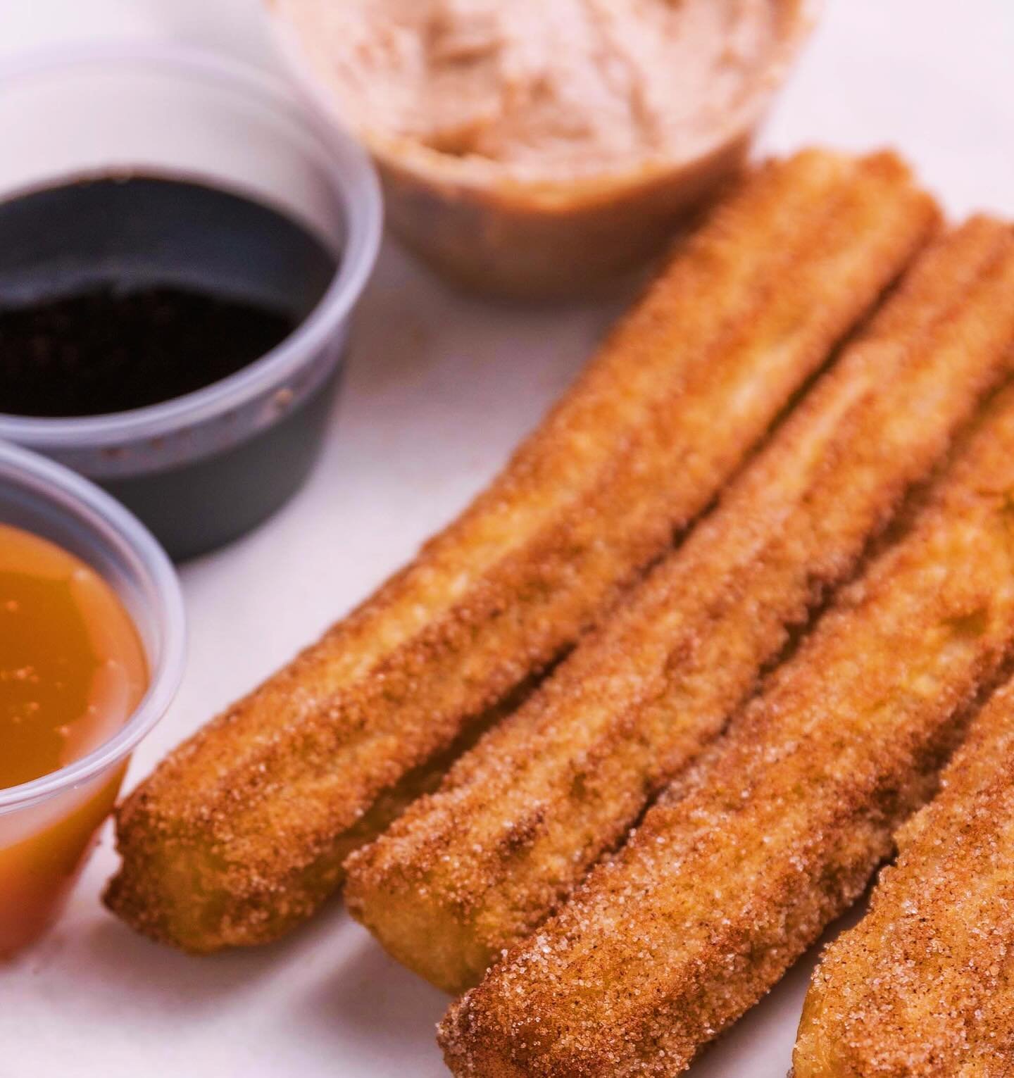Hey, check out our awesome Mini Churros Platter, man! 😎 Five of our homemade mini churros, rolled in cinnamon sugar and ready to rock your taste buds. Served with groovy chocolate, lime cream, and caramel sauce for some far-out dipping action. Order