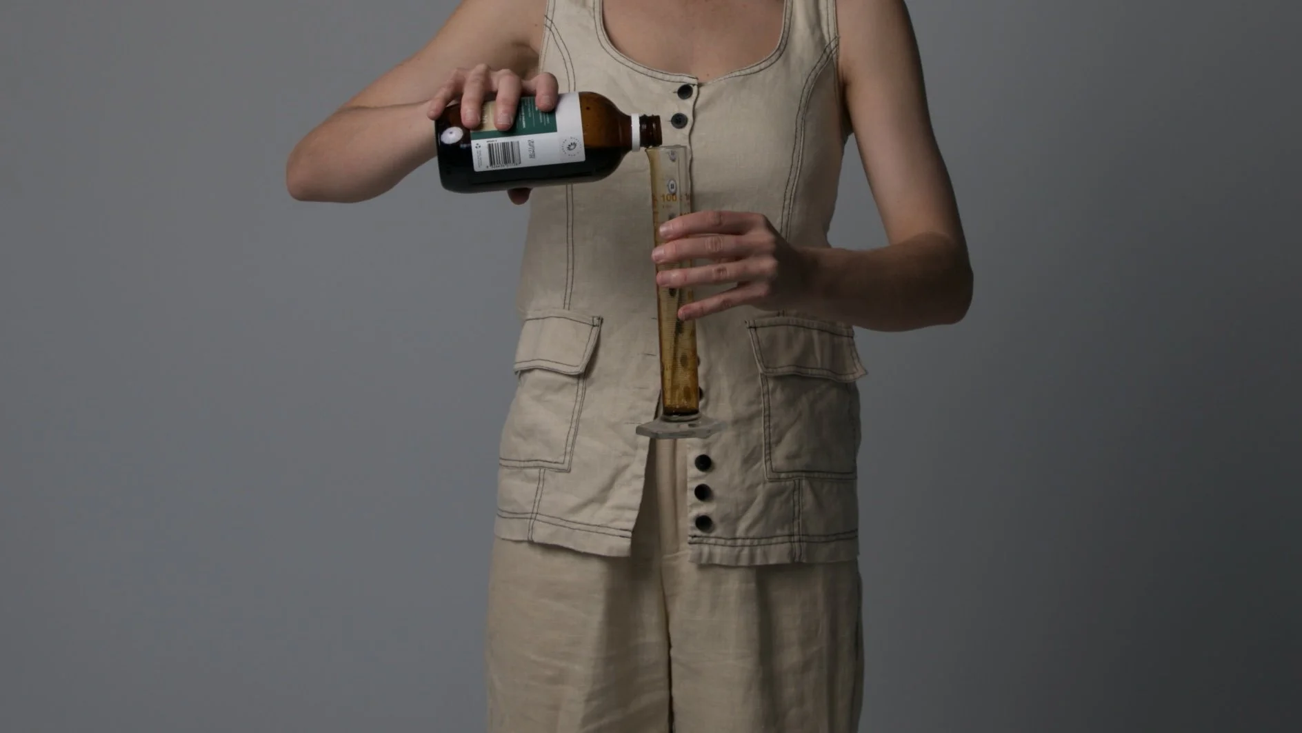 Person pouring medicine from a bottle into a syringe.