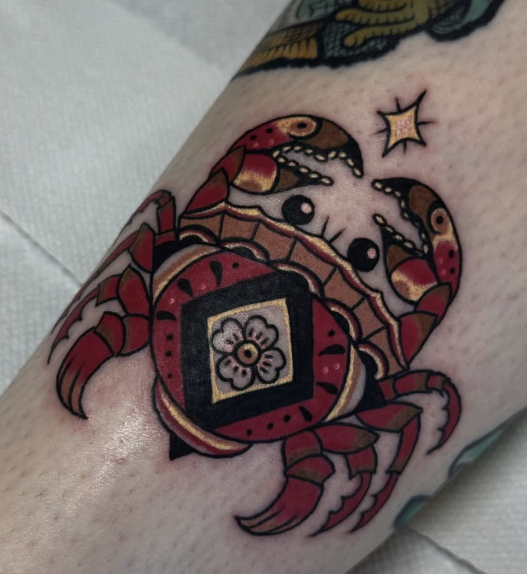 A colorful crab tattoo with black and gold accents, wearing a flower hat in a traditional style.