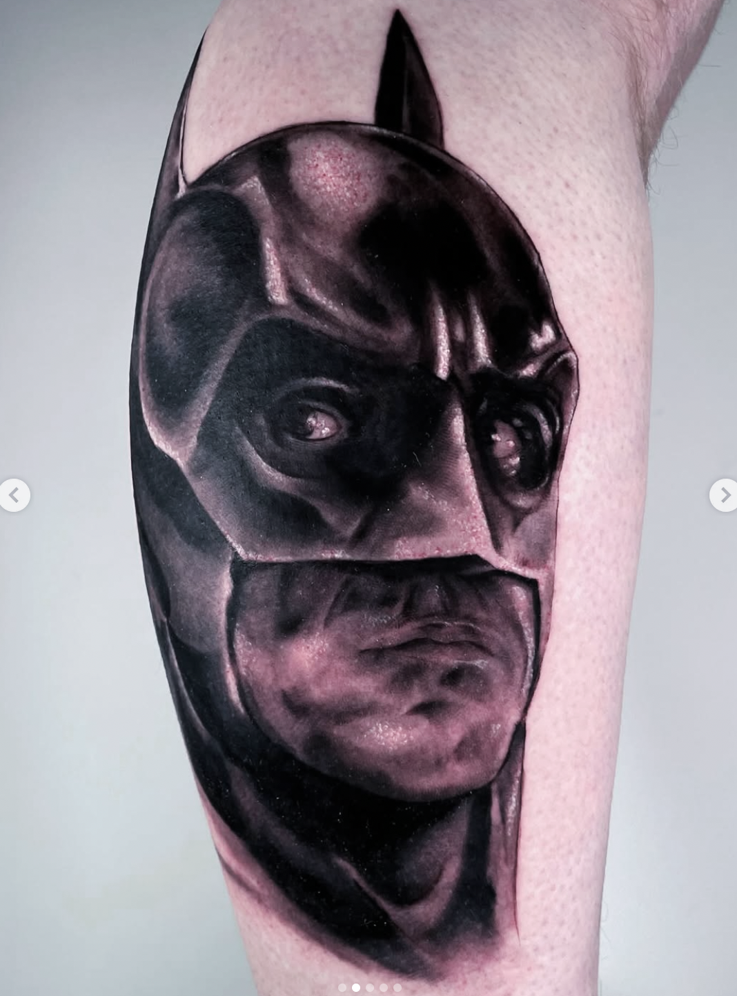 A realistic black-and-gray tattoo of a dog (a bulldog), alternating with a human face, on part of the arm.