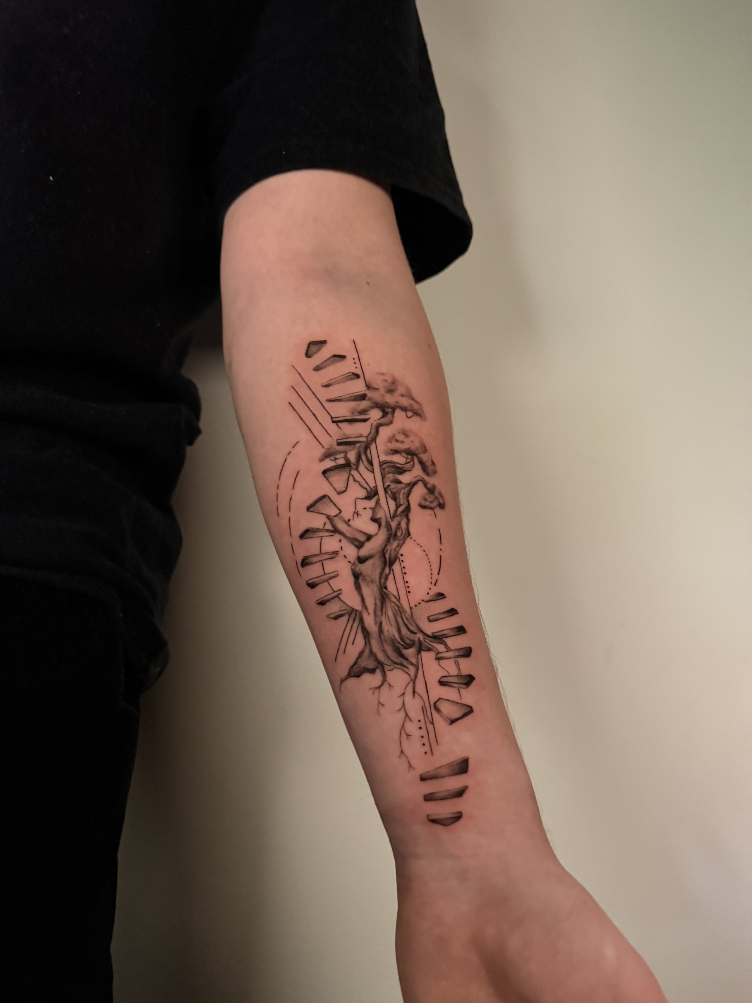 A tattoo of a running human figure, surrounded by lines and geometric shapes, located on a person's forearm.