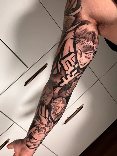 Tattoo of an anime character, with scary faces, on a person's arm.