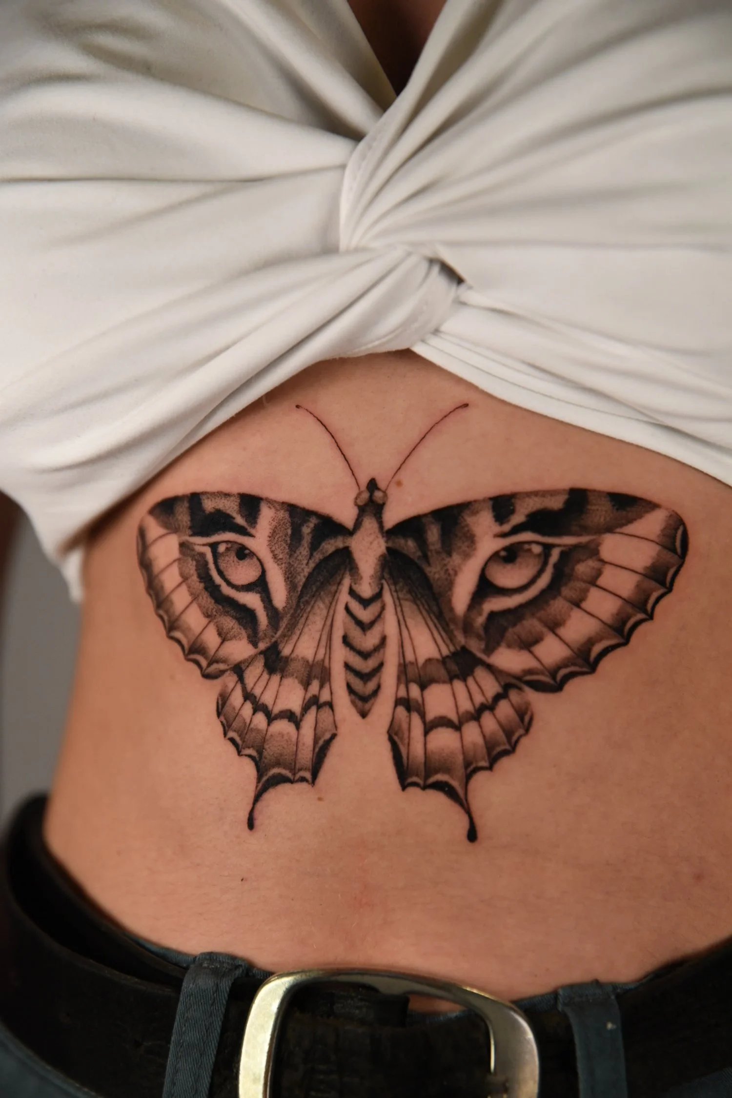 Tattoo of a butterfly with tiger eyes on the skin.
