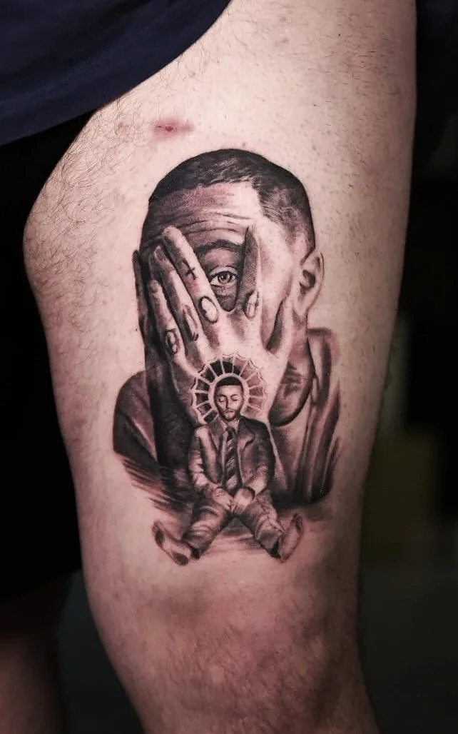 Tattoo depicting a man with a hand covering one eye, and a small man with a halo seated in a meditation position underneath.