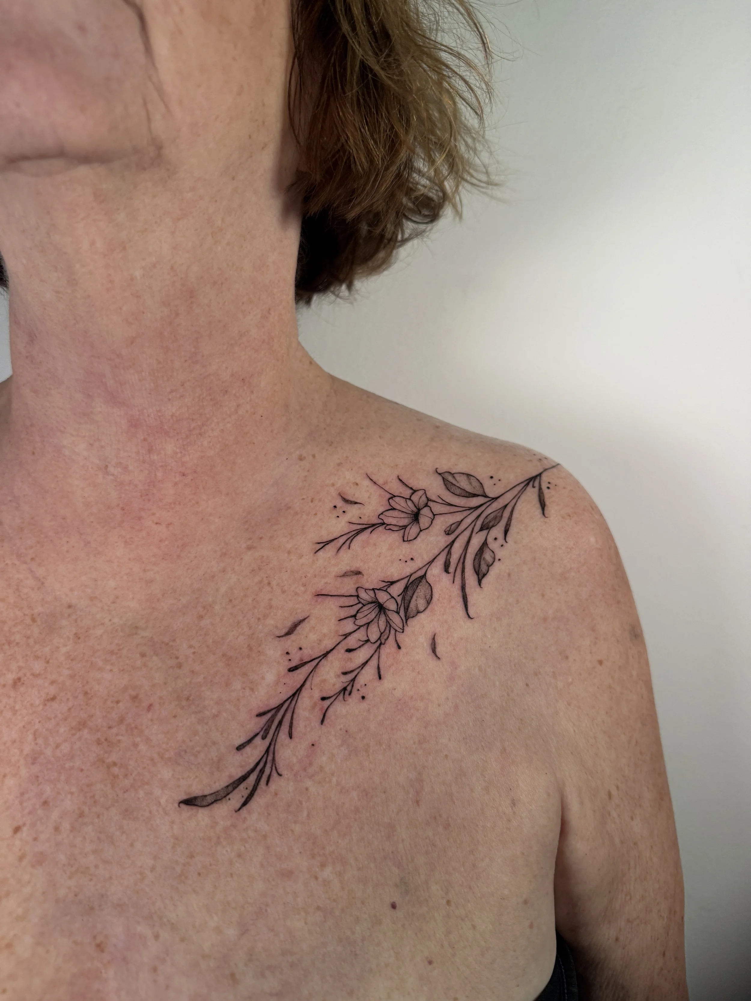 Black floral tattoo on a woman's right shoulder
