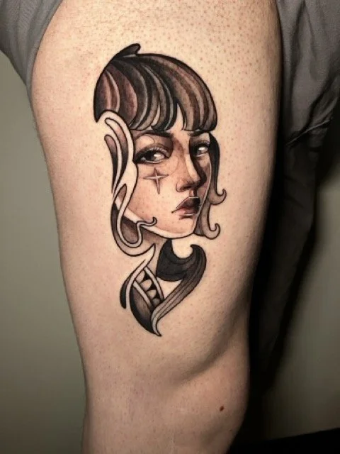 Tattoo of a woman with an expressive face on the thigh