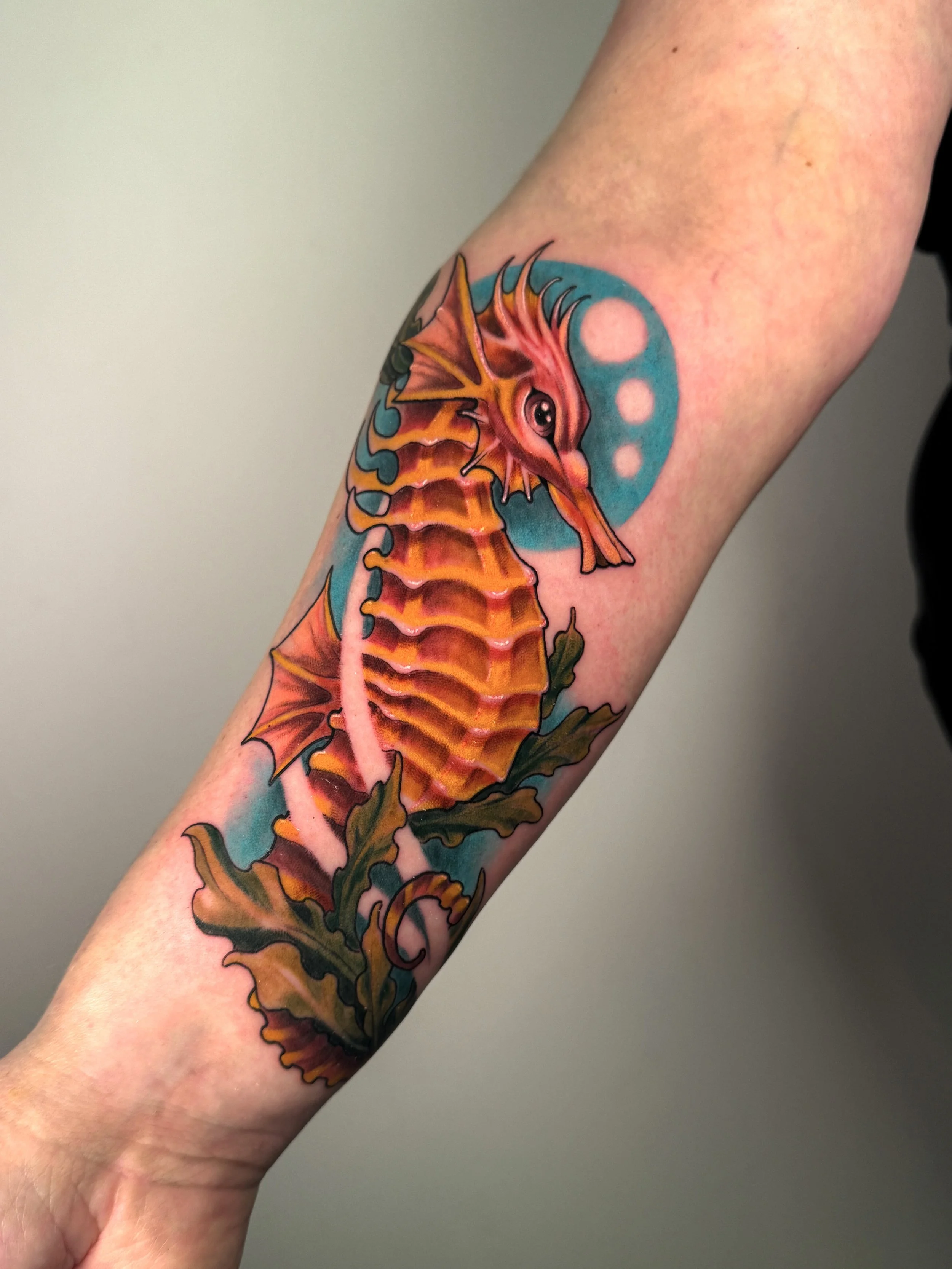 Tatouage d'un dragon orange et rouge sur le bras, avec un fond bleu
