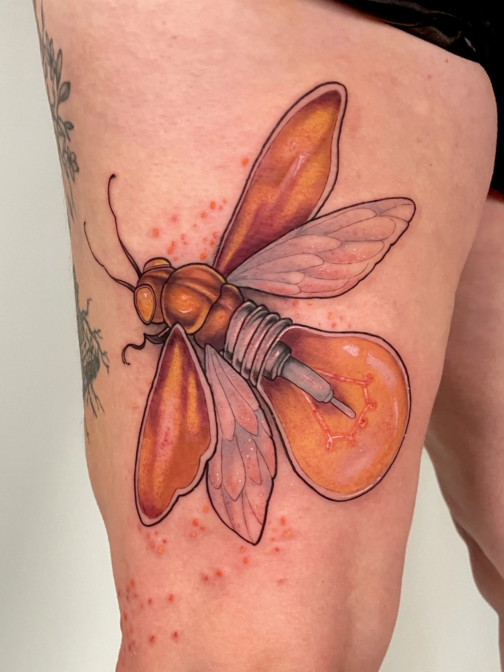 Tatouage d'une abeille stylisée avec des couleurs orange et brunes sur la peau d'une personne.
