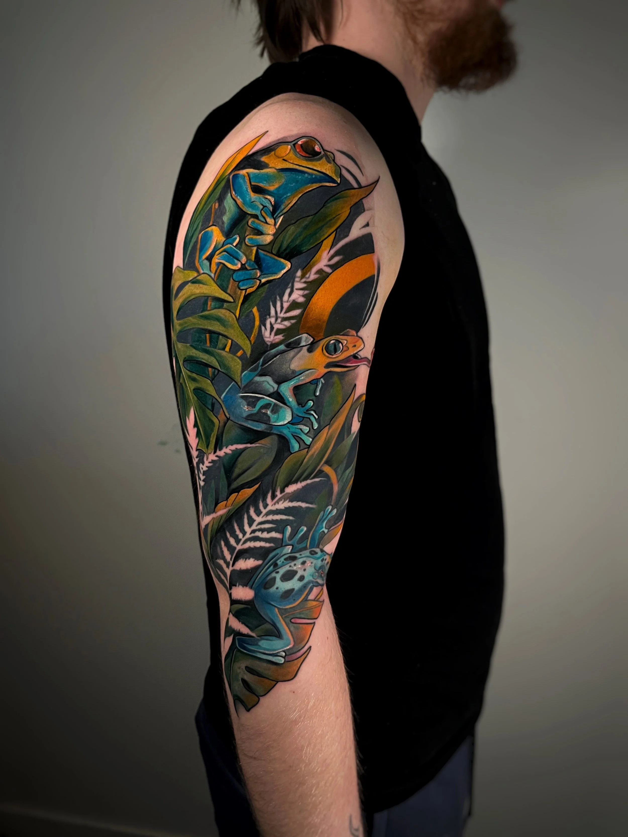 A colorful tattoo depicting two frogs on a man's arm.