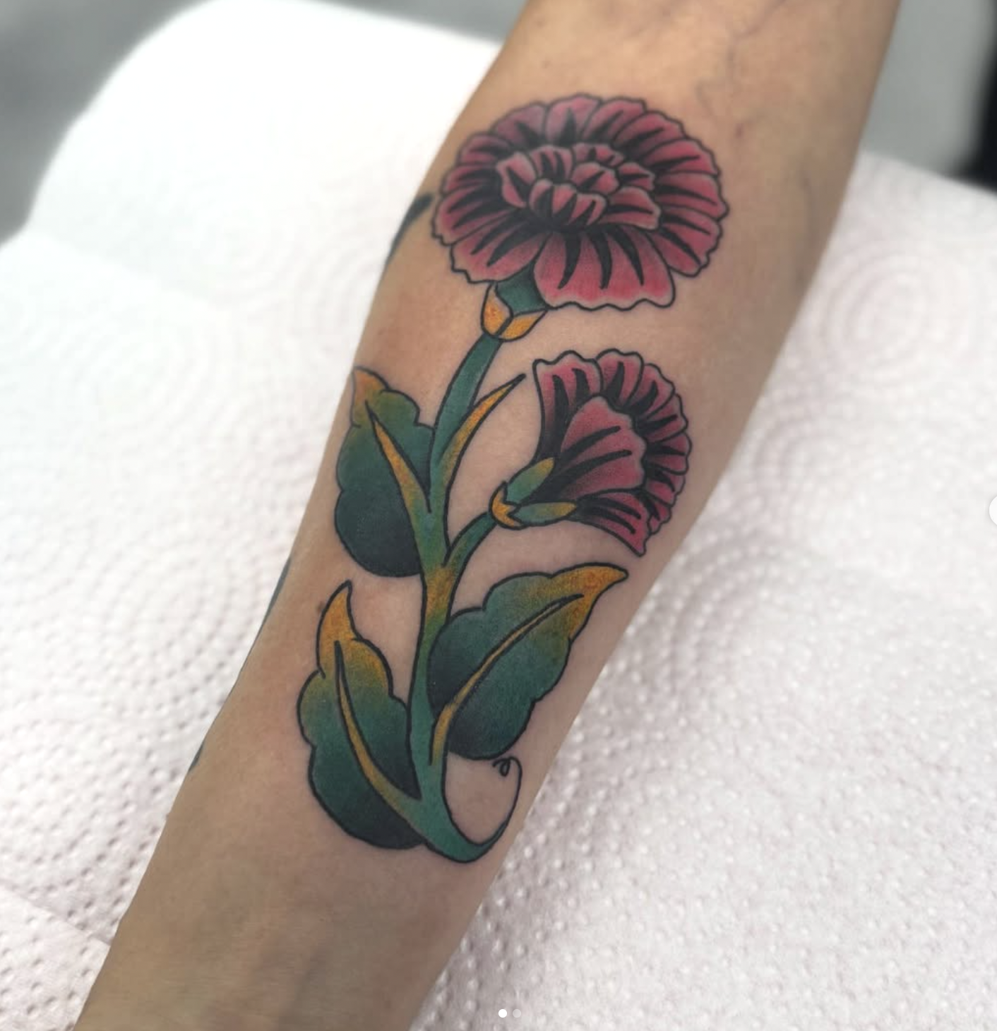 Tattoo of two pink flowers on an arm