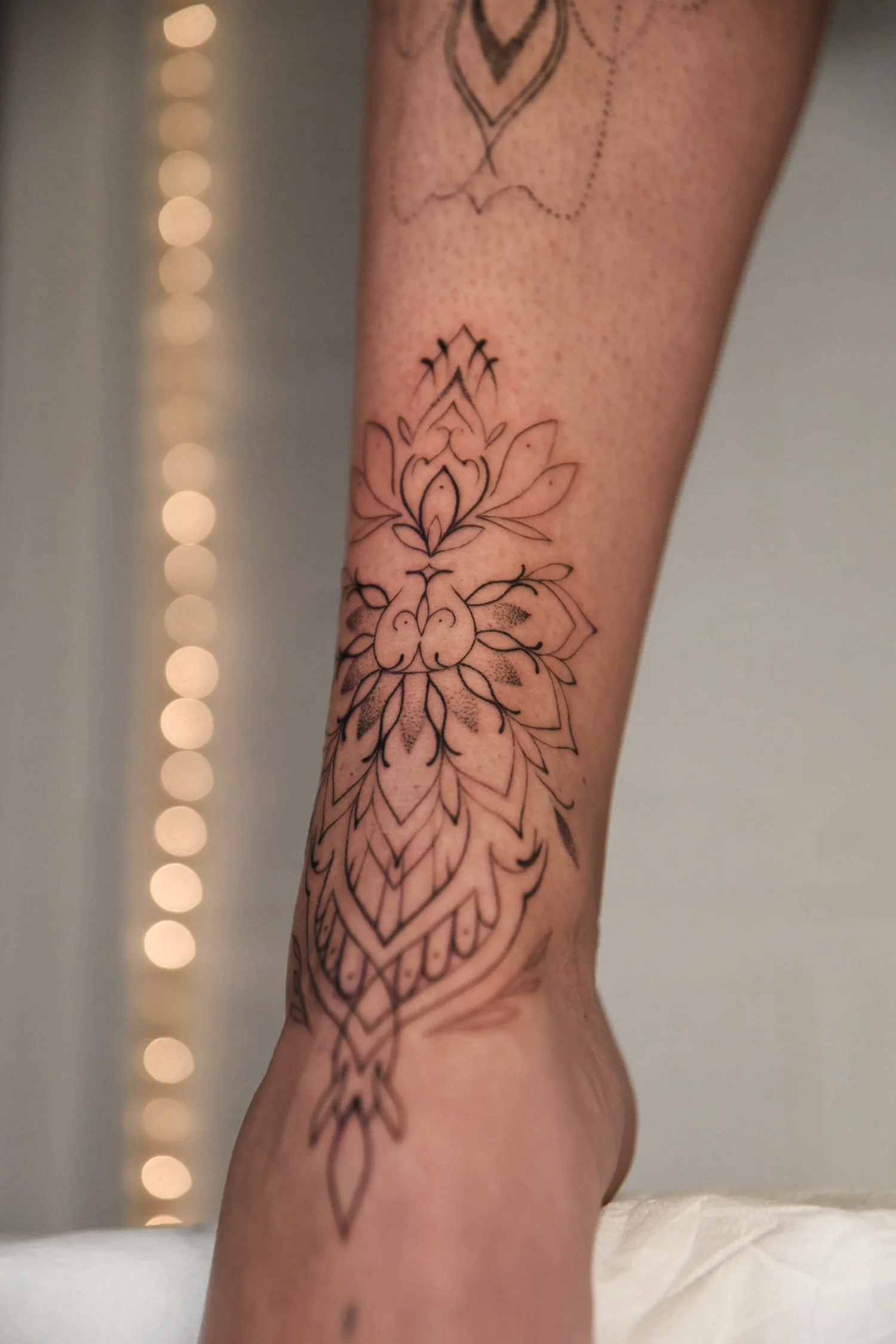 Decorative black tattoo on one leg, featuring floral and geometric motifs.