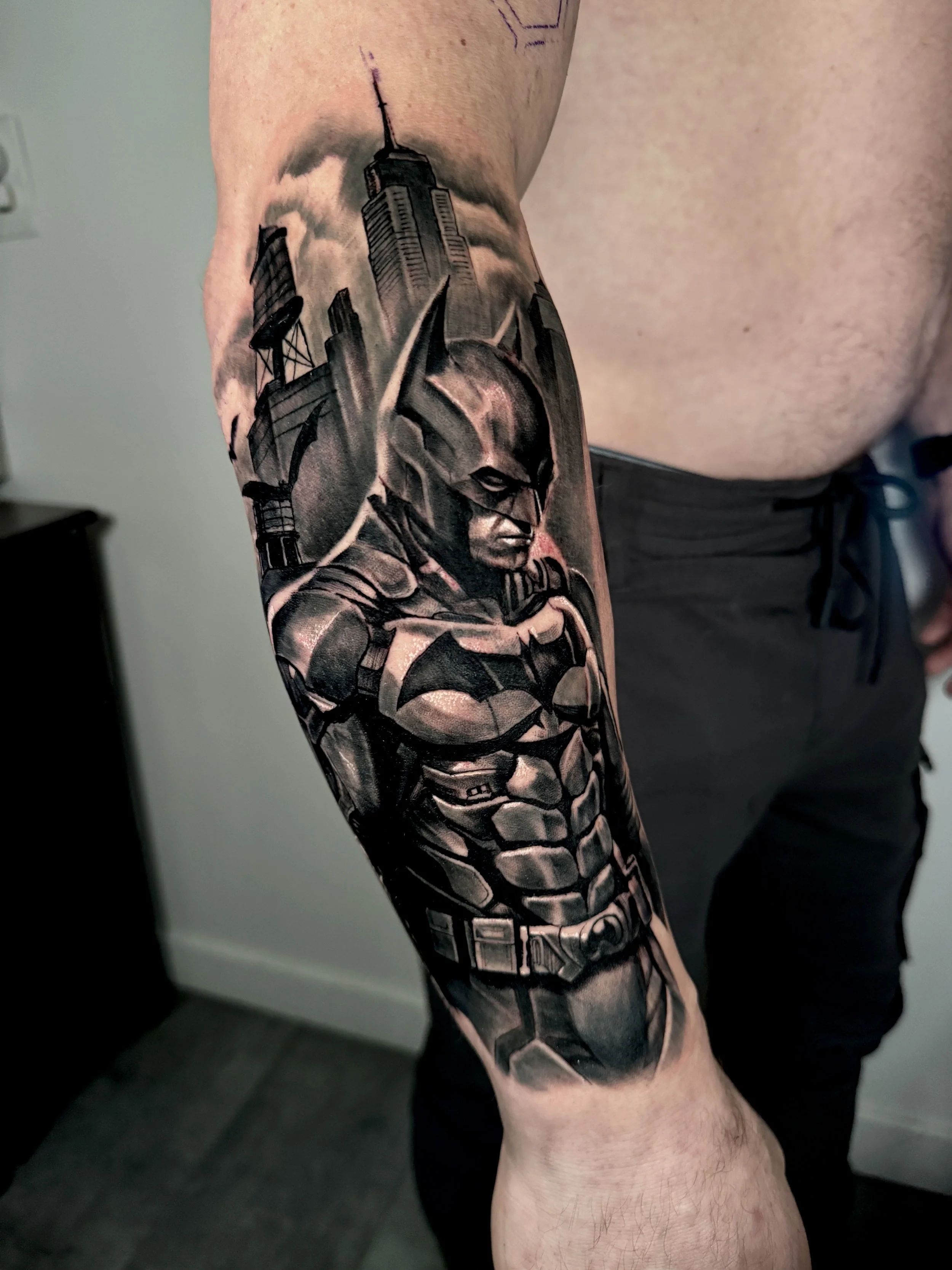 A tattoo of Batman on someone's arm, with a city in the background—probably Gotham City.