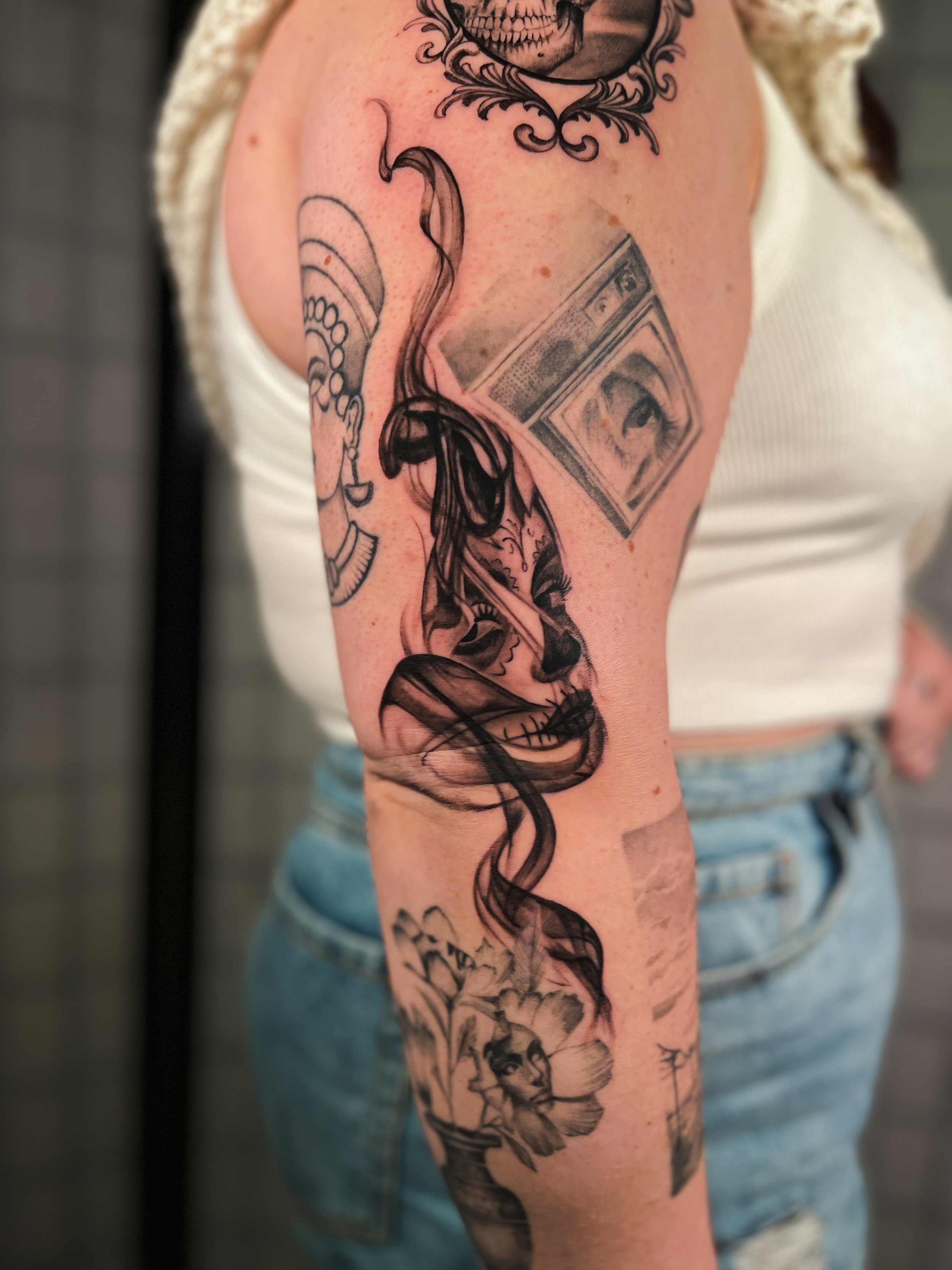 Tattoo of a woman in steam, with a woman's face and flower motifs, on a person's arm